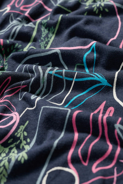 Close-up of the T-shirt’s fabric showing colourful floral linework in pink, green, and blue.