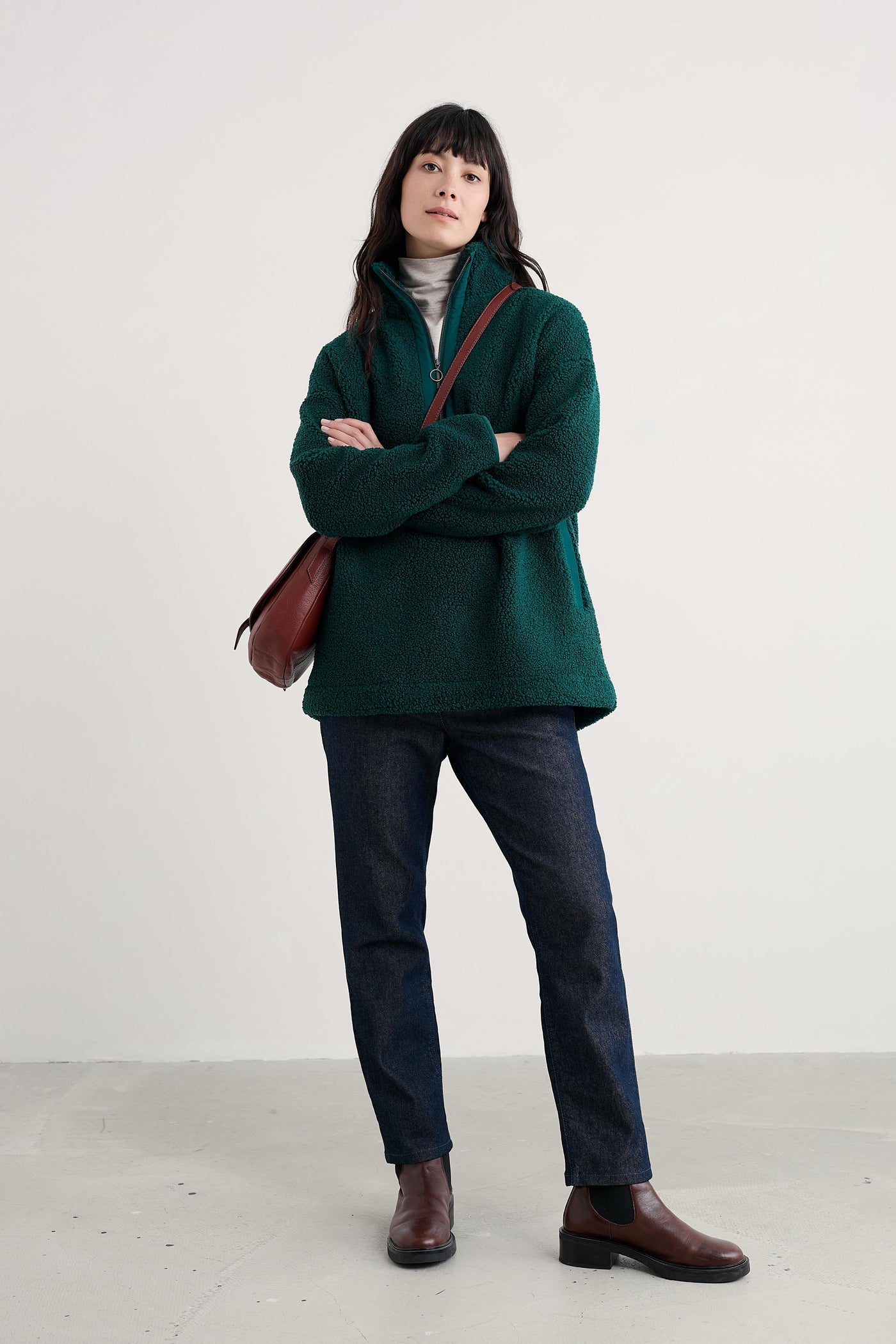 Woman wearing a green fleece with crossed arms on a plain background
