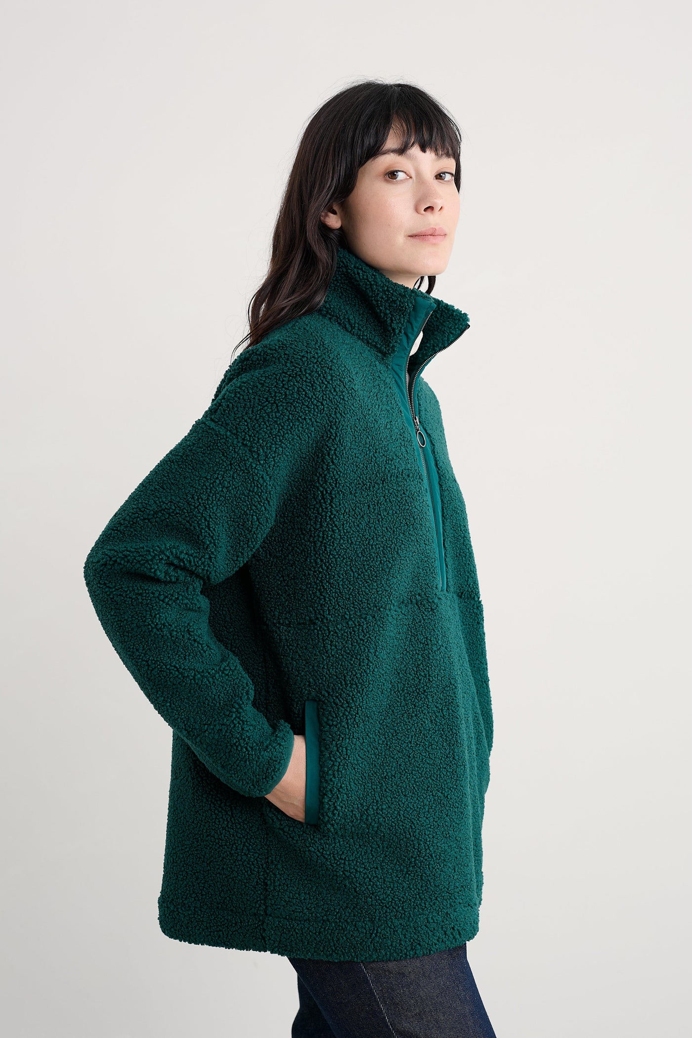 Person wearing a green fleece jacket on a plain background