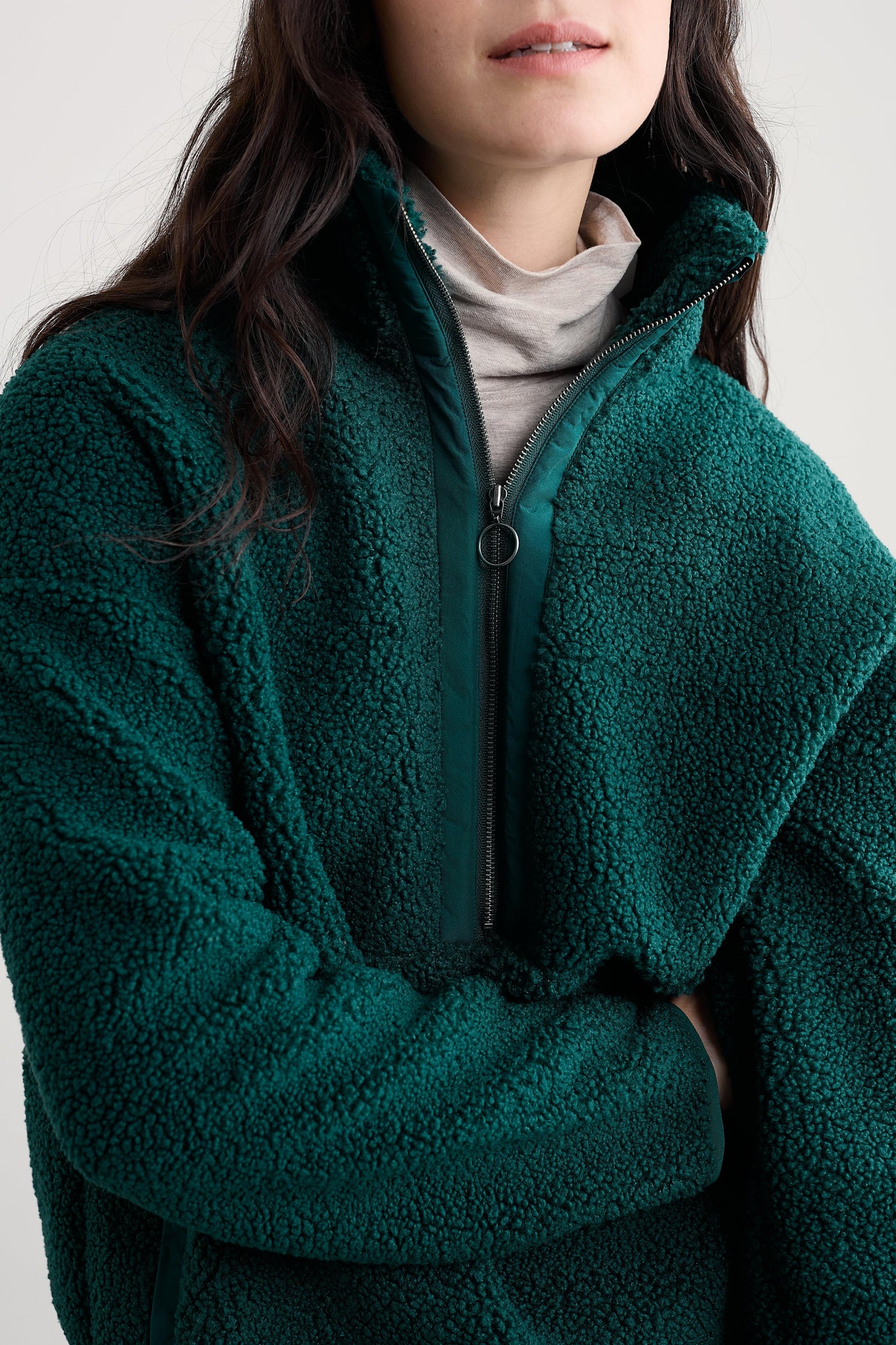 Person wearing a green fleece jacket with half zip on a plain background
