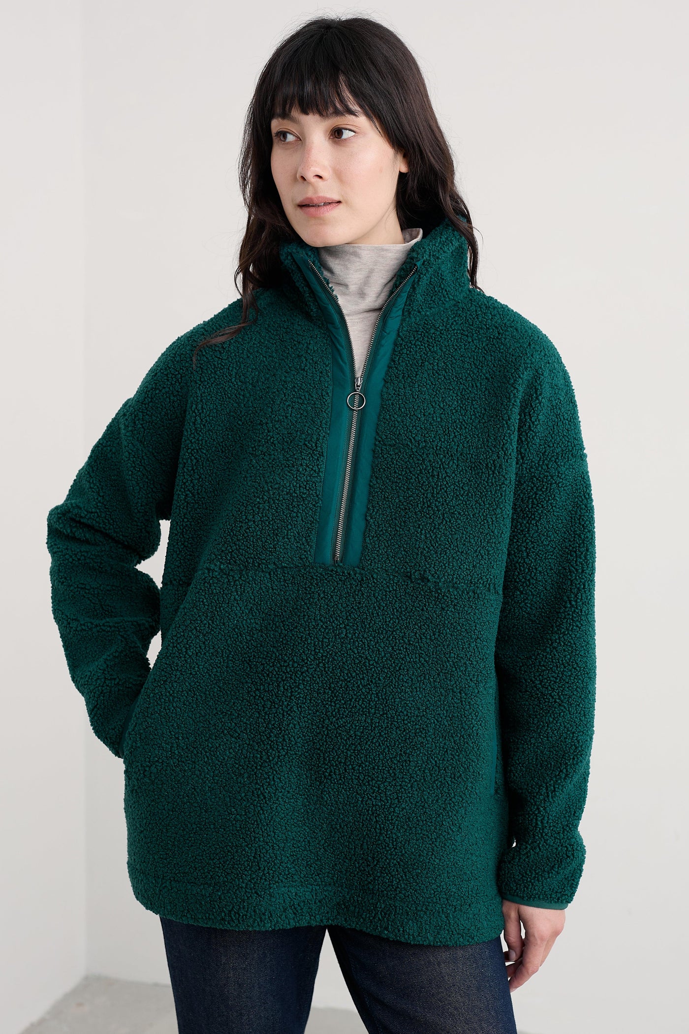 Woman wearing an oversized green fleece pullover against a white background