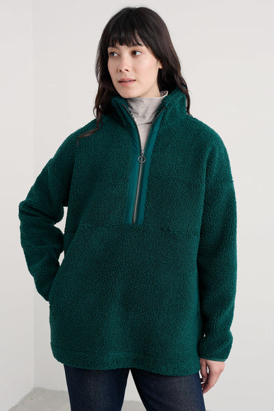 Woman wearing an oversized green fleece pullover against a white background