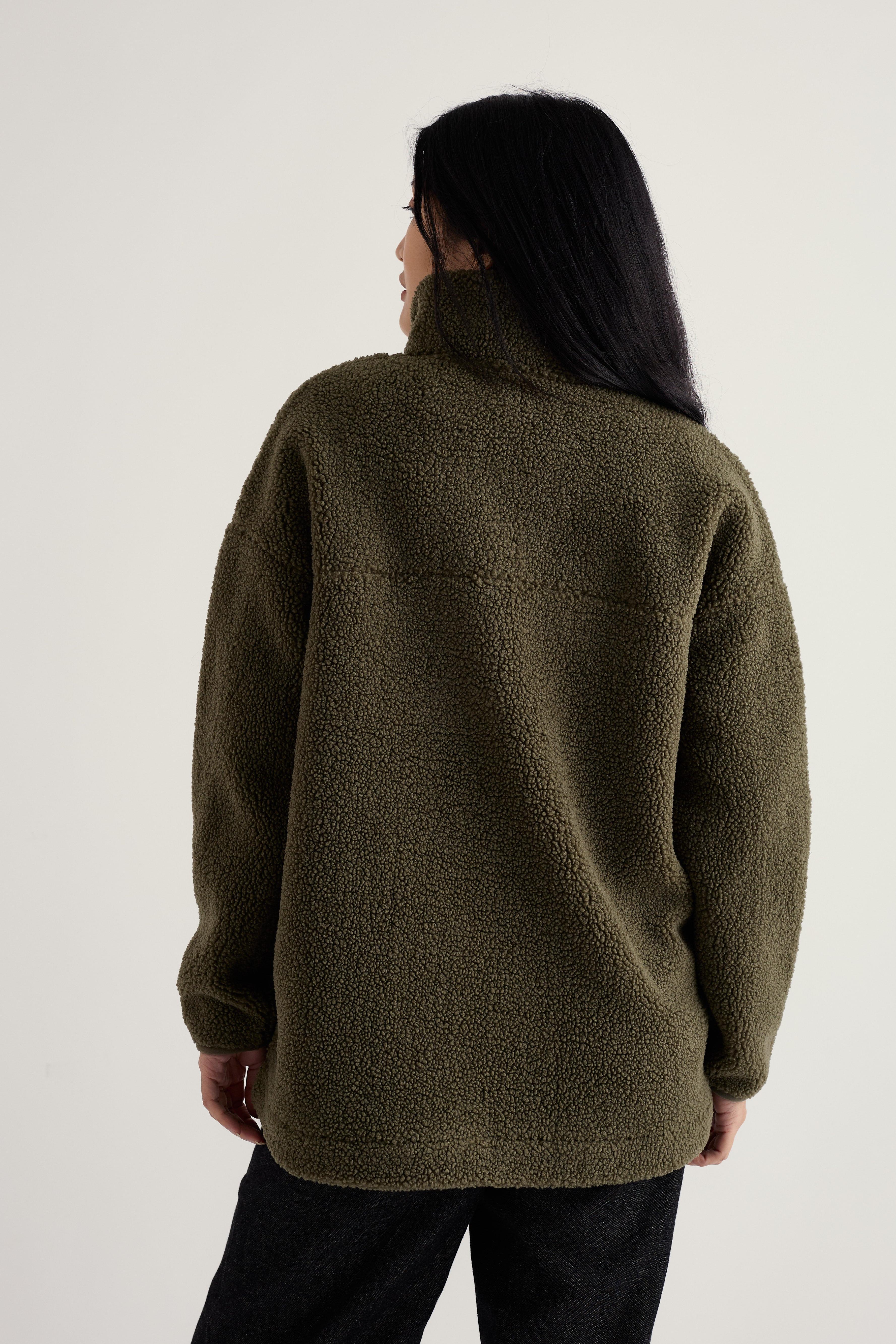 Person wearing a green fleece jacket on a plain background