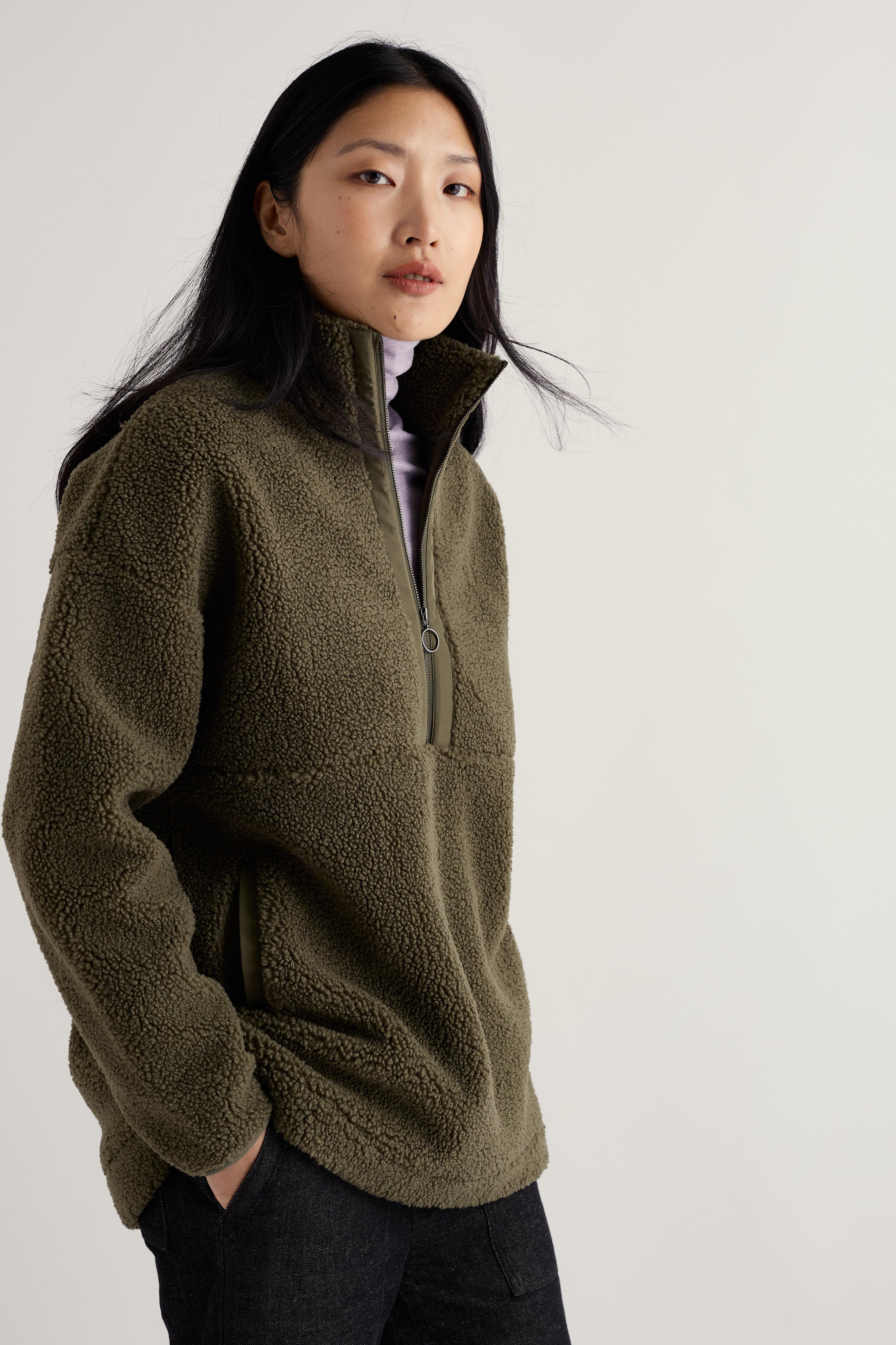 Woman wearing a green fleece pullover against a plain background