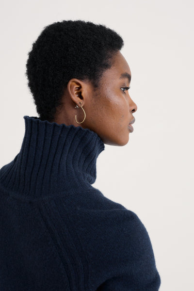 Woman wearing a dark blue turtleneck sweater against a light background
