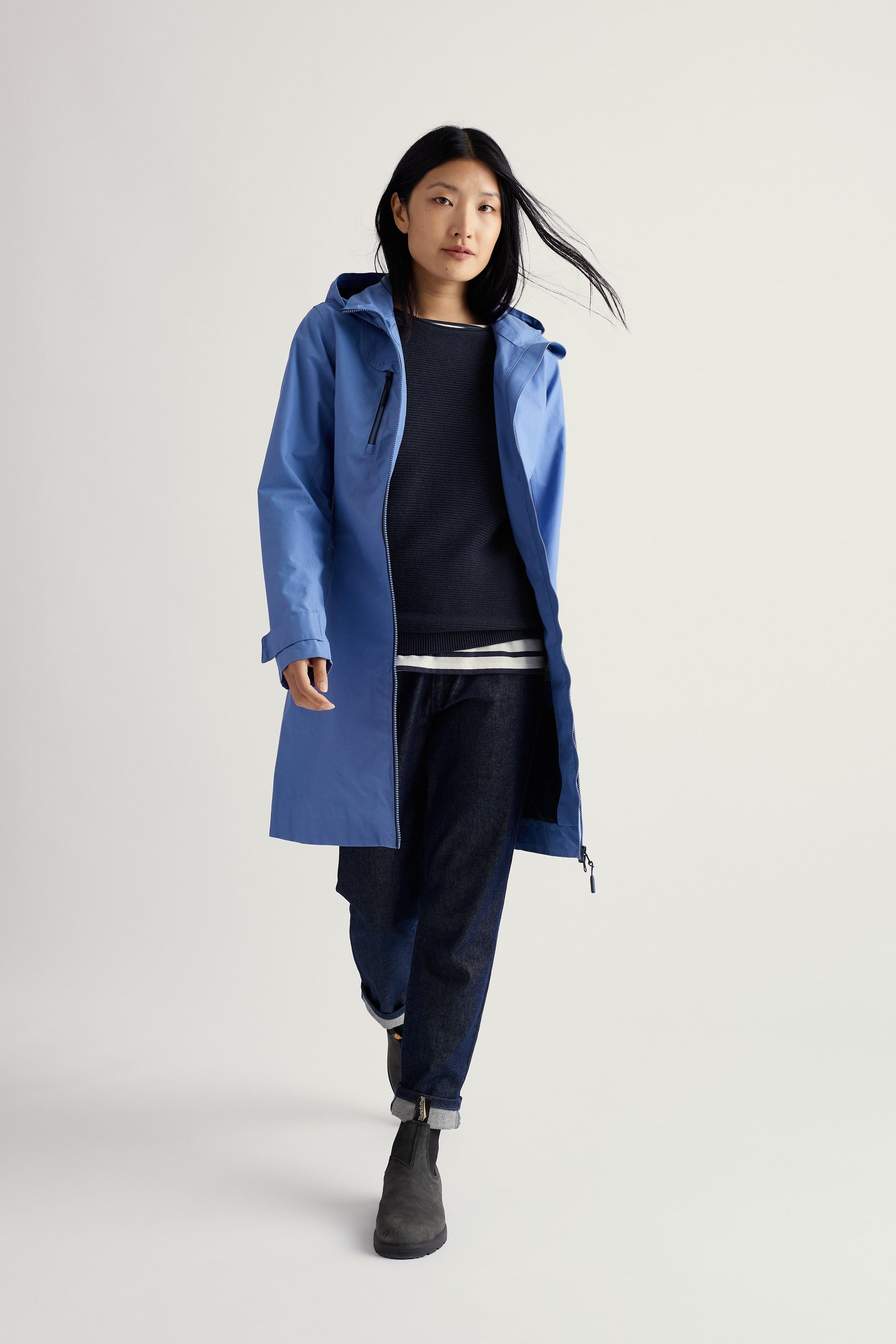 Person wearing a blue raincoat on a plain background