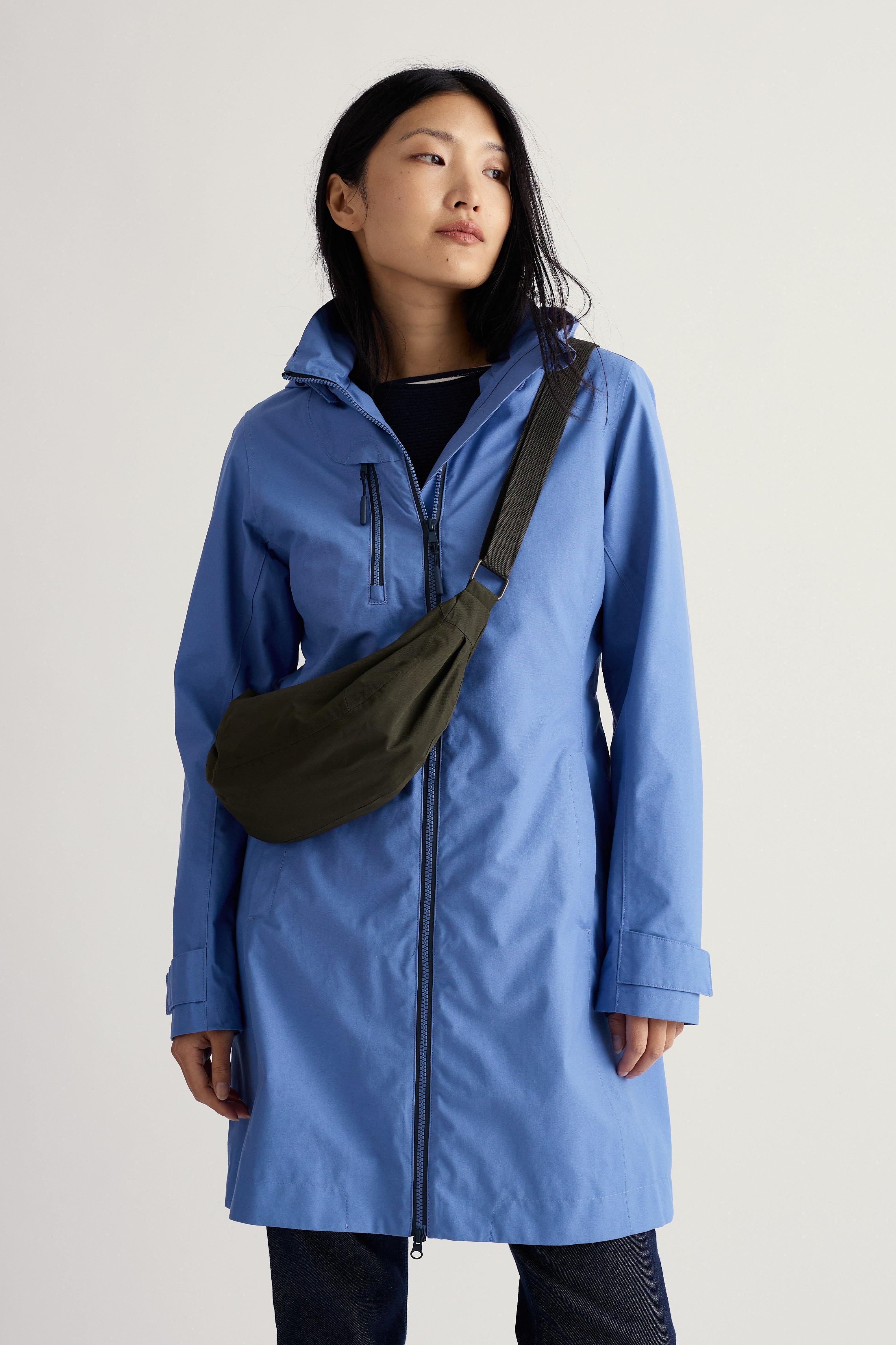 Person wearing a blue coat with a black bag on a light gray background
