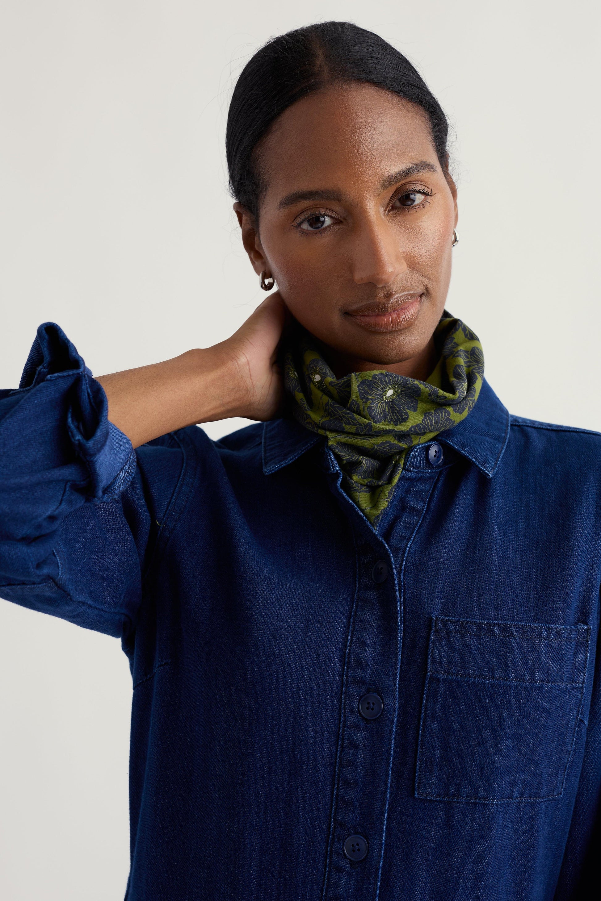 Woman wearing a blue shirt and patterned organic cotton scarf against a plain background