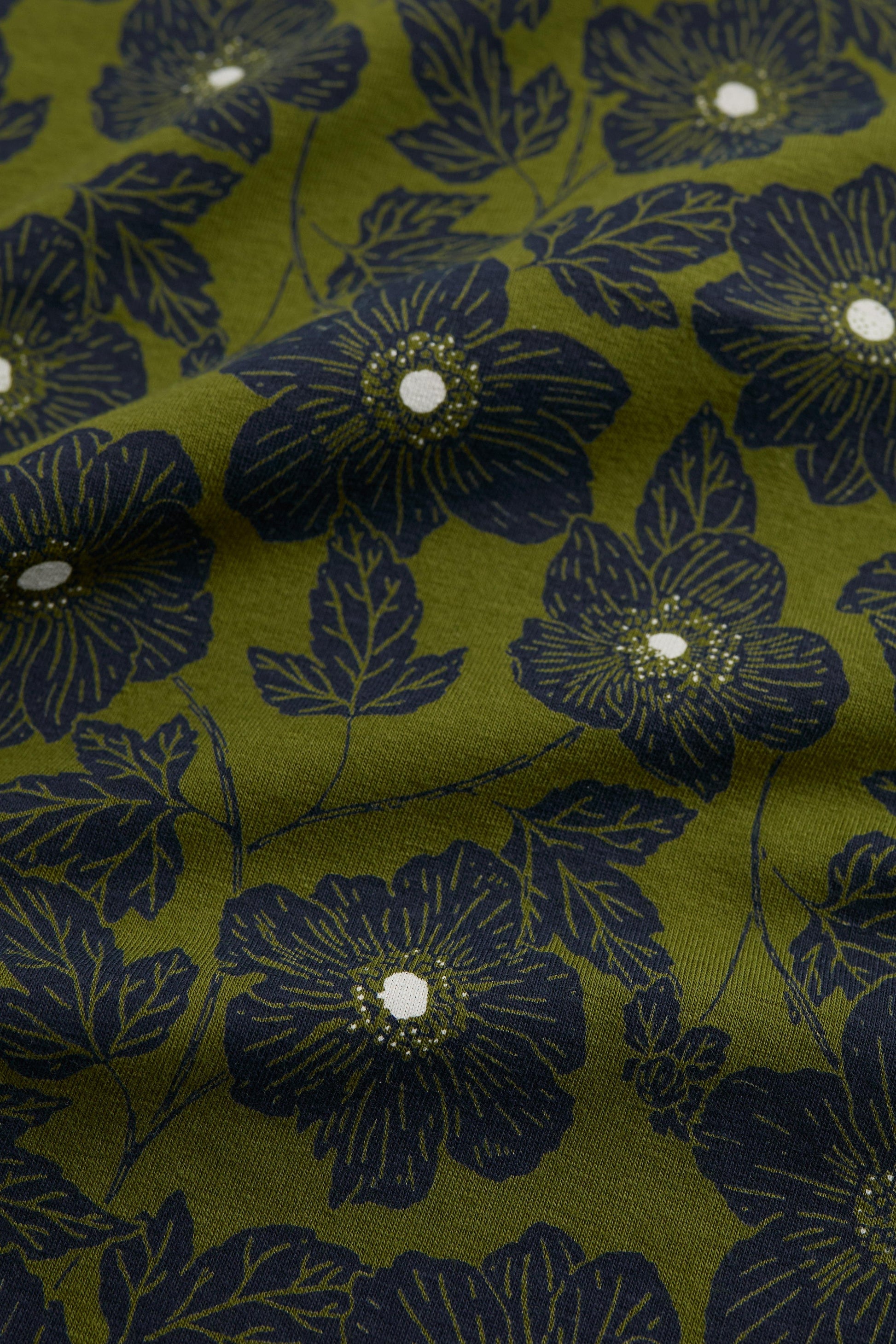 Floral patterned fabric with dark blue flowers on a green background