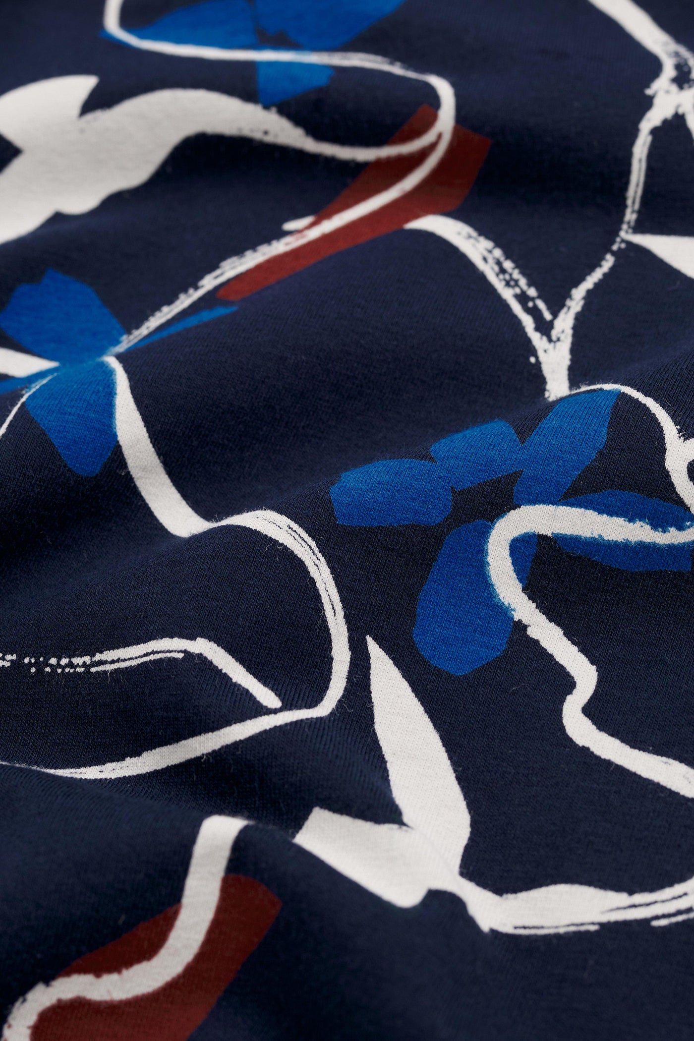 Close-up of fabric with blue, white, and red floral pattern on a dark background