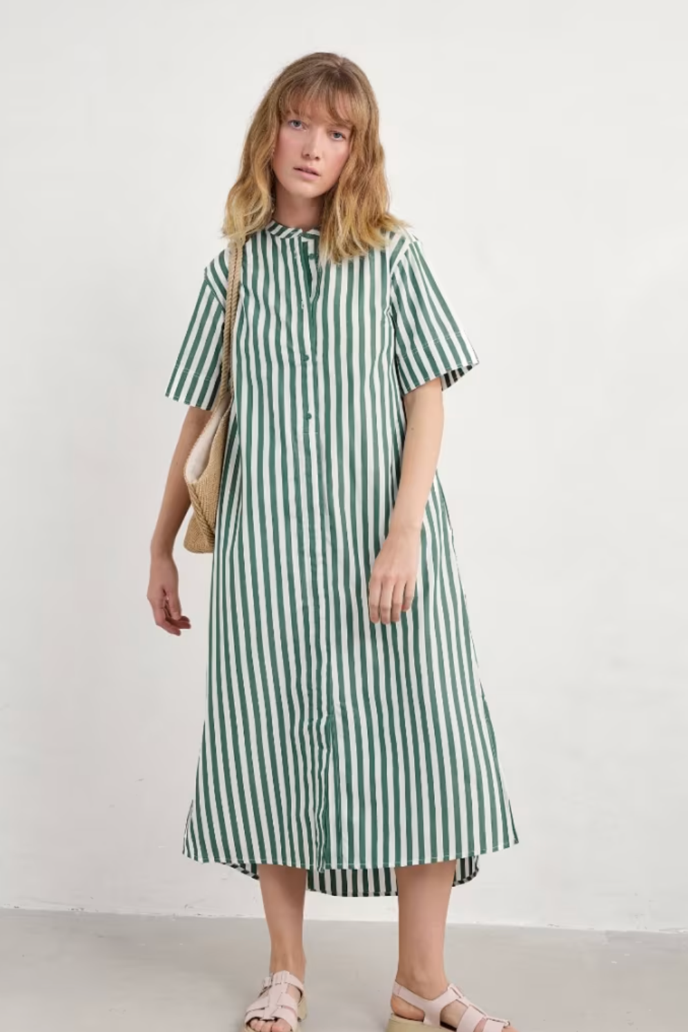 Full front view of model wearing Seasalt Harbour Movement Dress in green and white stripes, standing with hands at sides.
