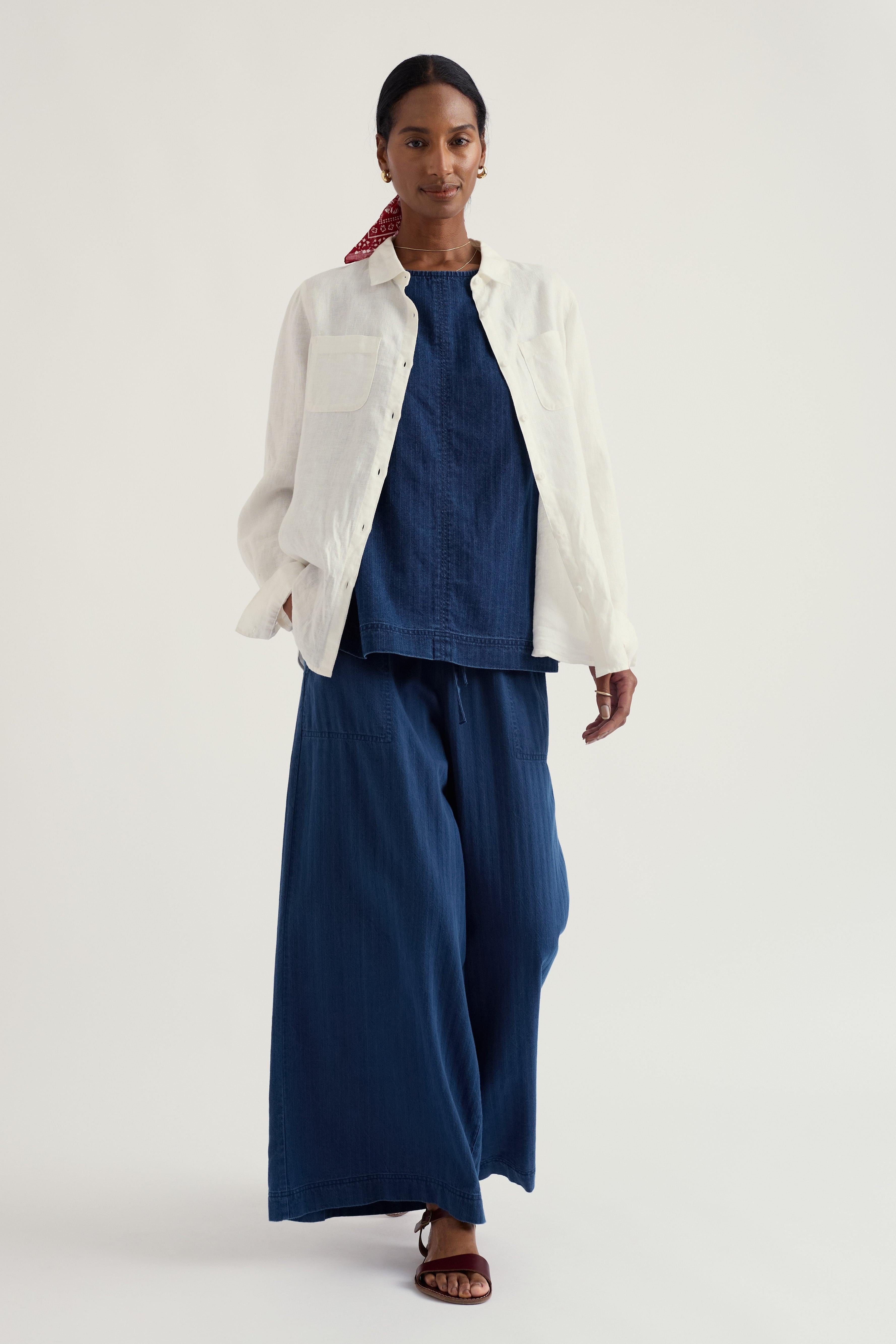 Woman wearing a white linen shirt over a blue outfit on a white background