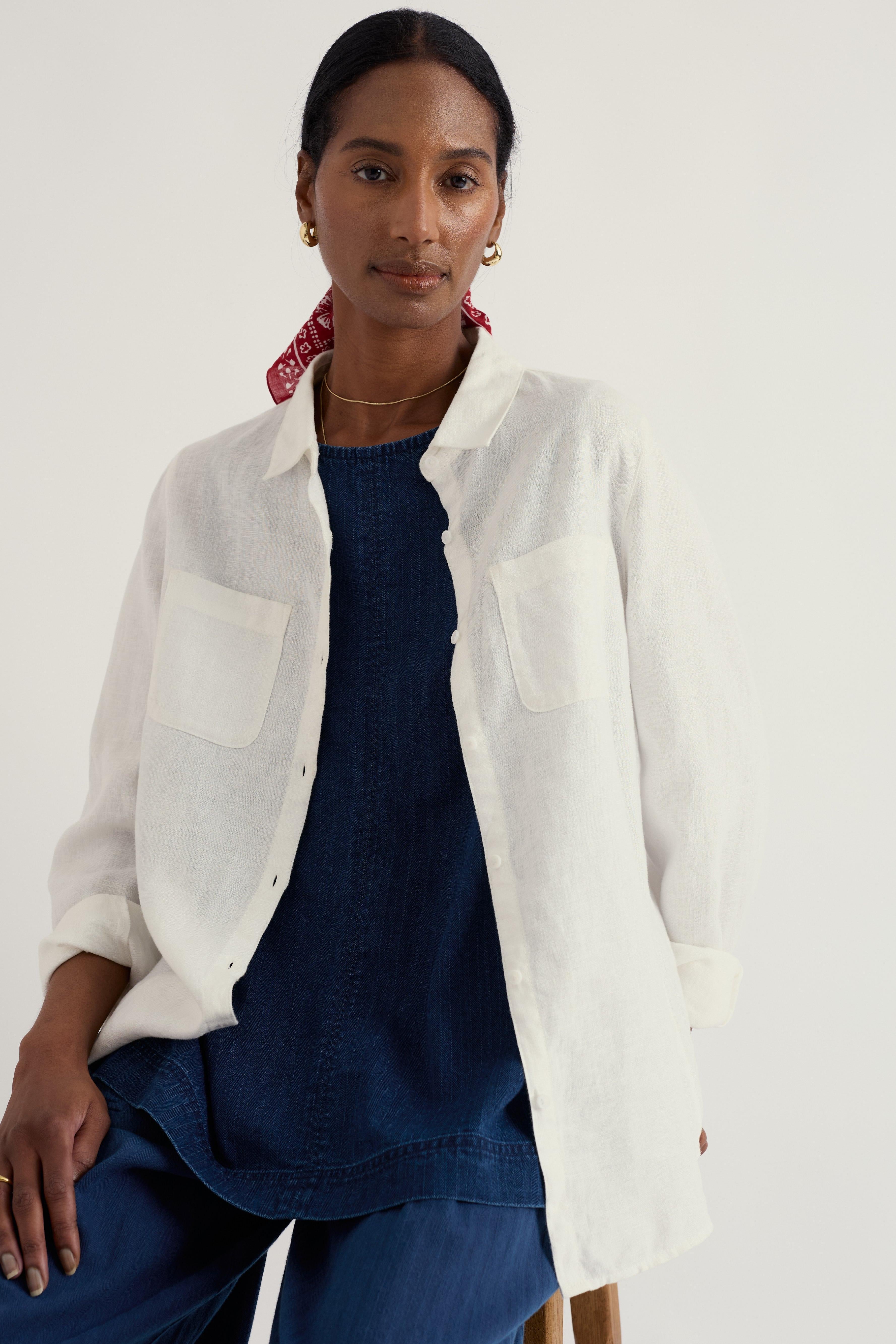 Woman wearing a white linen shirt over a navy outfit with a red headband against a white background