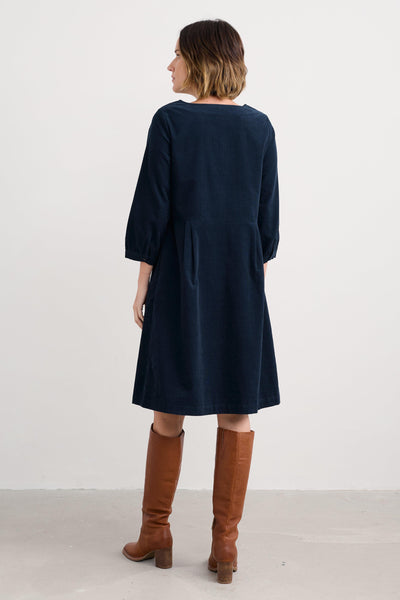 Woman wearing a navy dress and brown knee-high boots on a white background