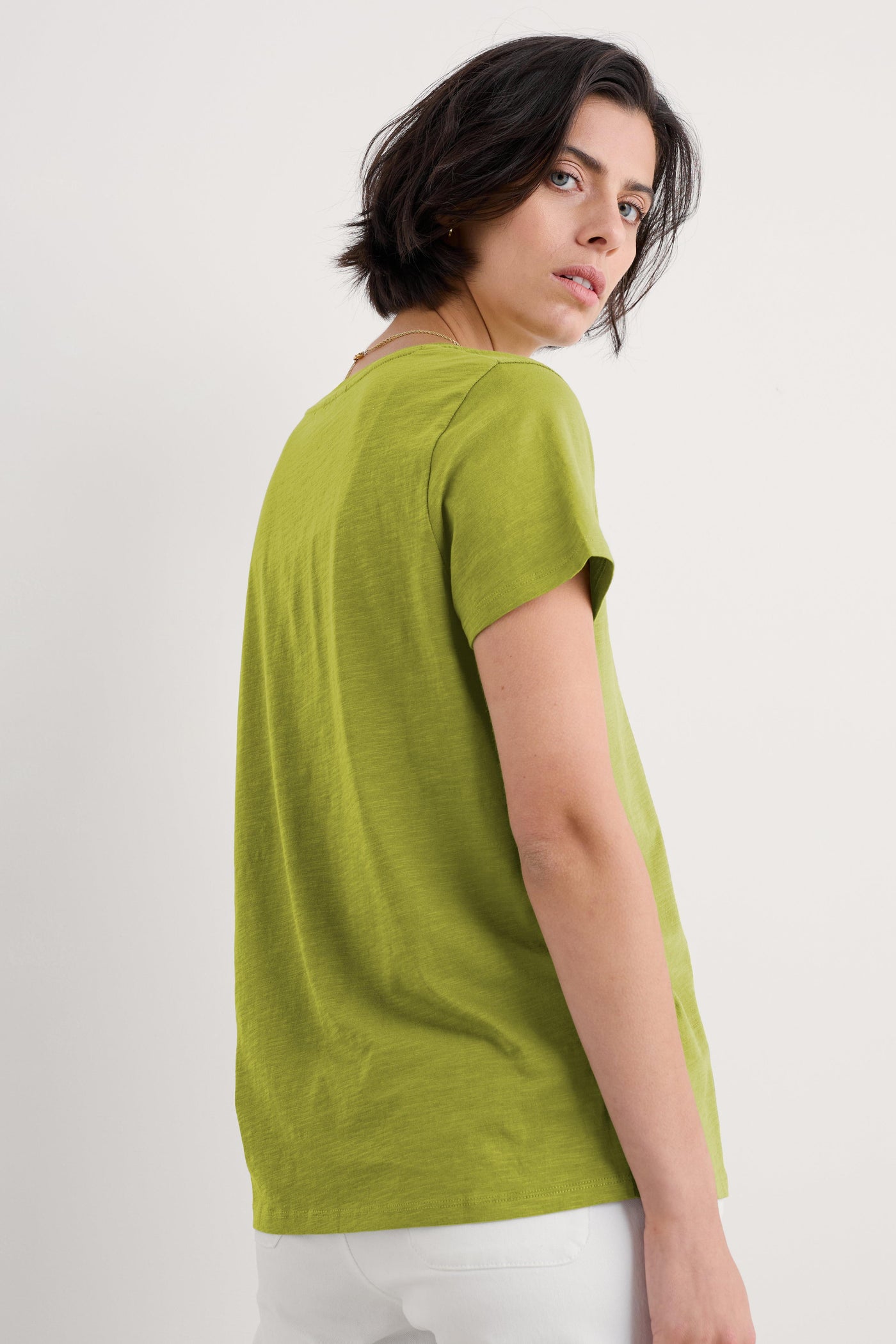 Side view of woman wearing the Seasalt Kellow T-Shirt in Dark Citron, showing relaxed fit and short sleeves.