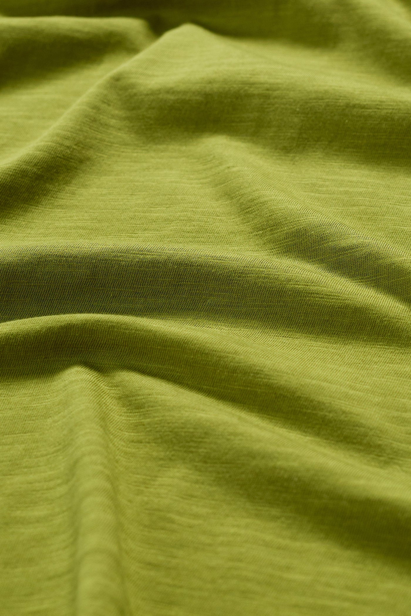 Close-up of the Seasalt Kellow T-Shirt fabric in Dark Citron, showing texture and stitching details.