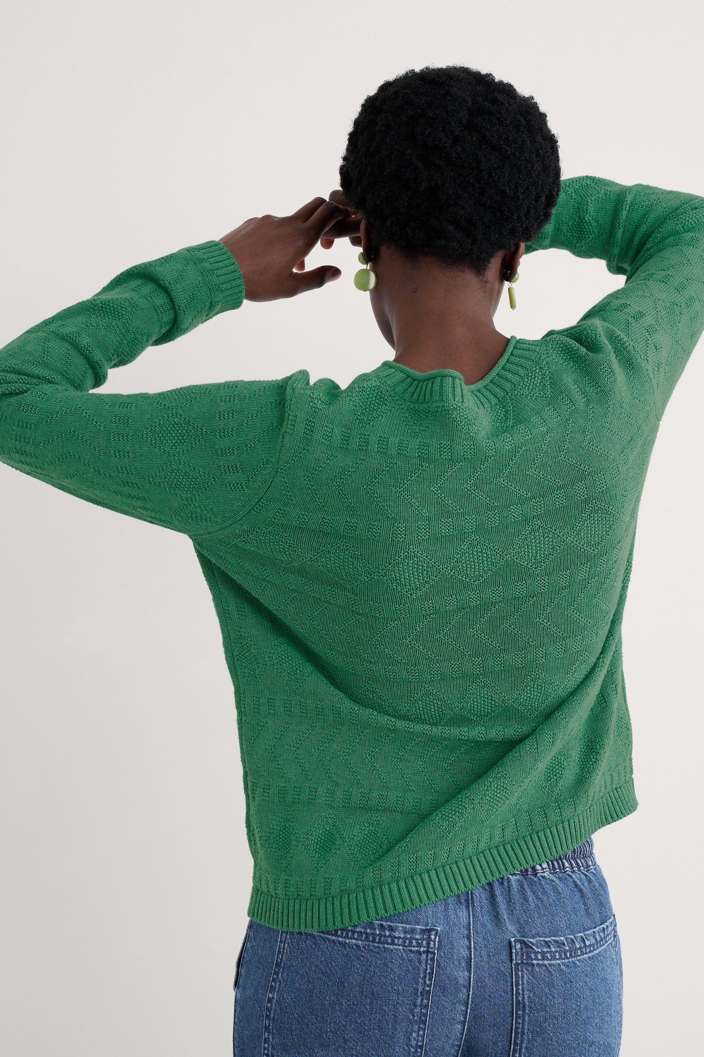 Rear view displaying the continuation of the tactile stitch patterns and the straight hemline of the jumper.