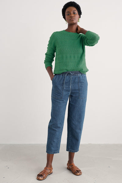 Model styled in the organic cotton jumper paired with denim jeans and brown sandals.
