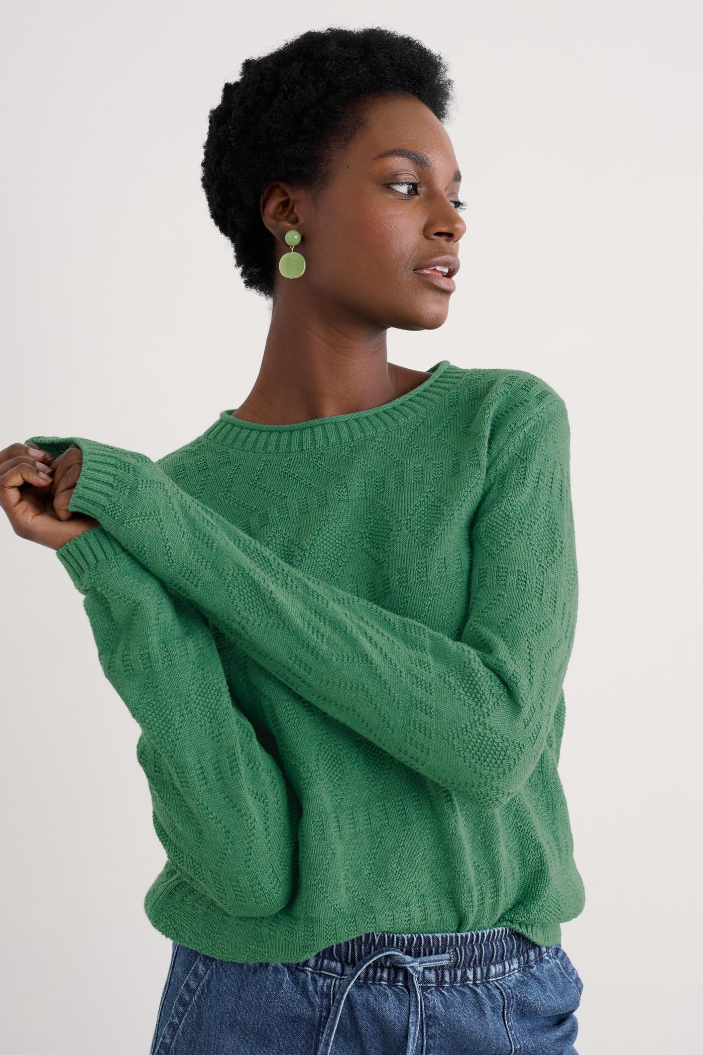 Model wearing the Seasalt Kinter Jumper in Knit Melange Pine, showcasing the crew neckline, long sleeves, and intricate textured stitch patterns.