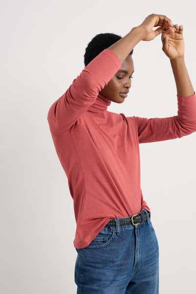 Person wearing a pink organic cotton long-sleeve top and blue jeans on a light background