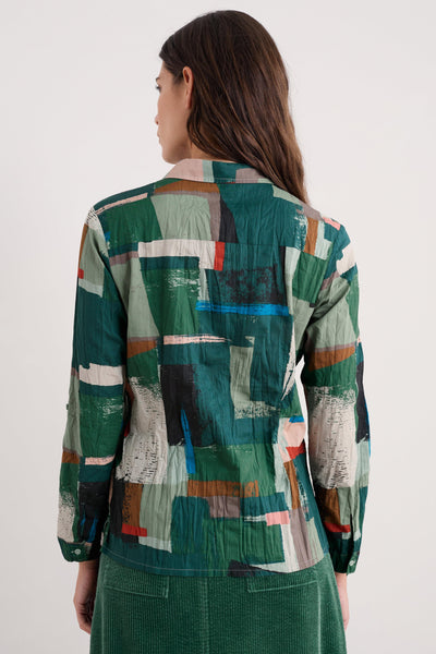 Person wearing a colorful geometric patterned shirt on a white background