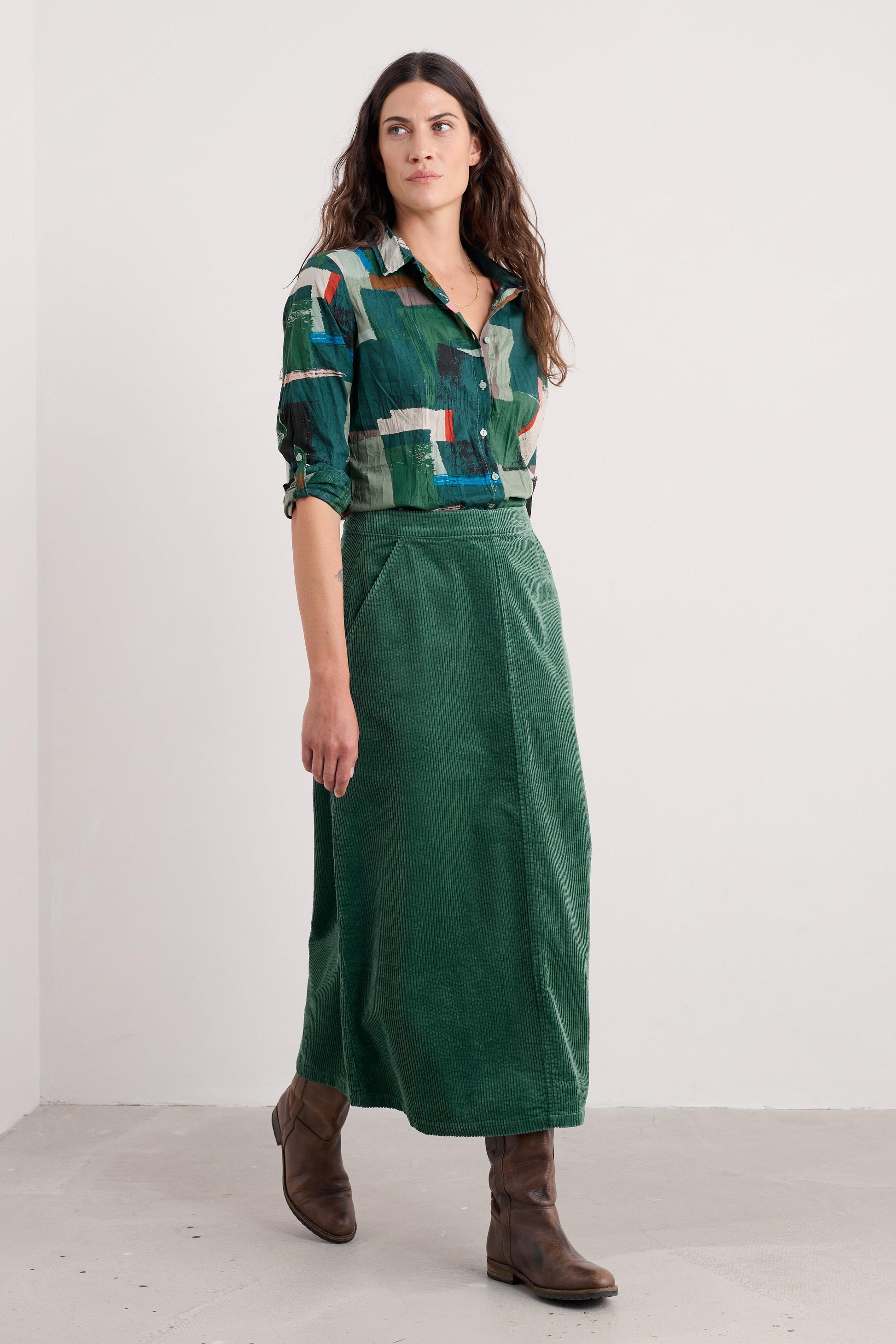 Woman wearing a patterned organic cotton shirt and green skirt against a white background