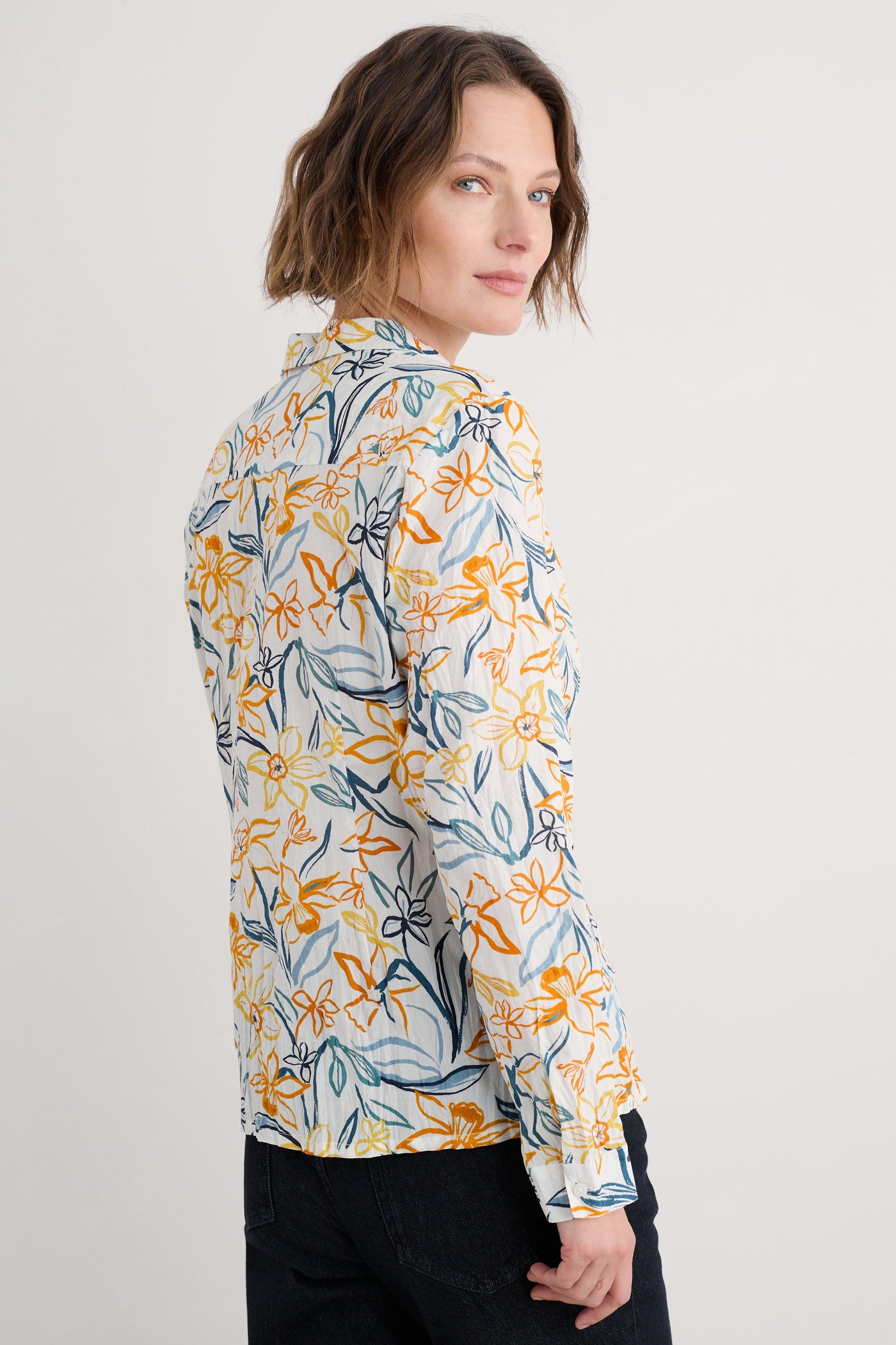 Side profile of the shirt highlighting the relaxed fit, curved hemline, and the vibrant floral print.