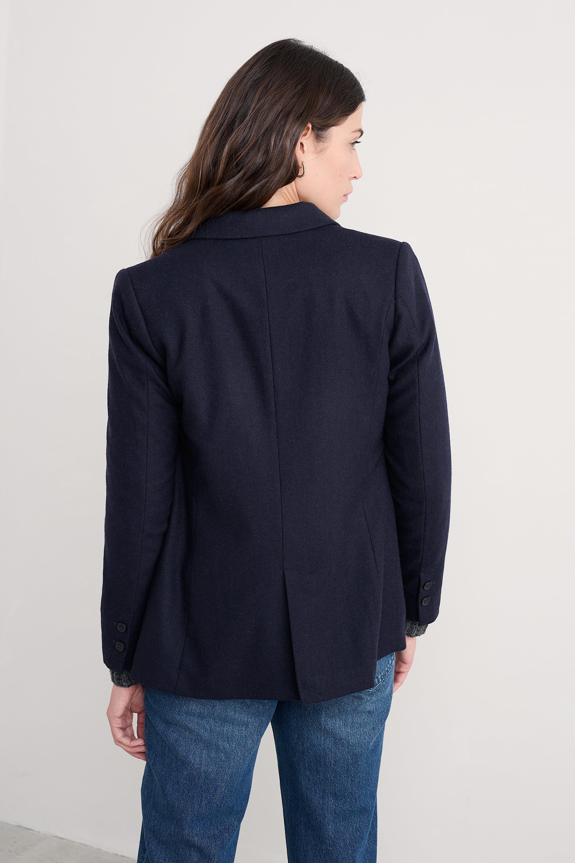 Person wearing a navy organic cotton blazer and blue jeans against a white background