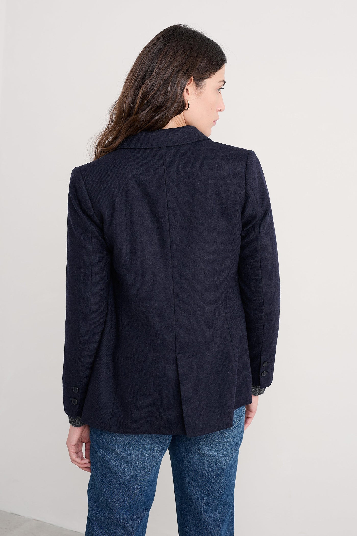 Person wearing a navy organic cotton blazer and blue jeans against a white background