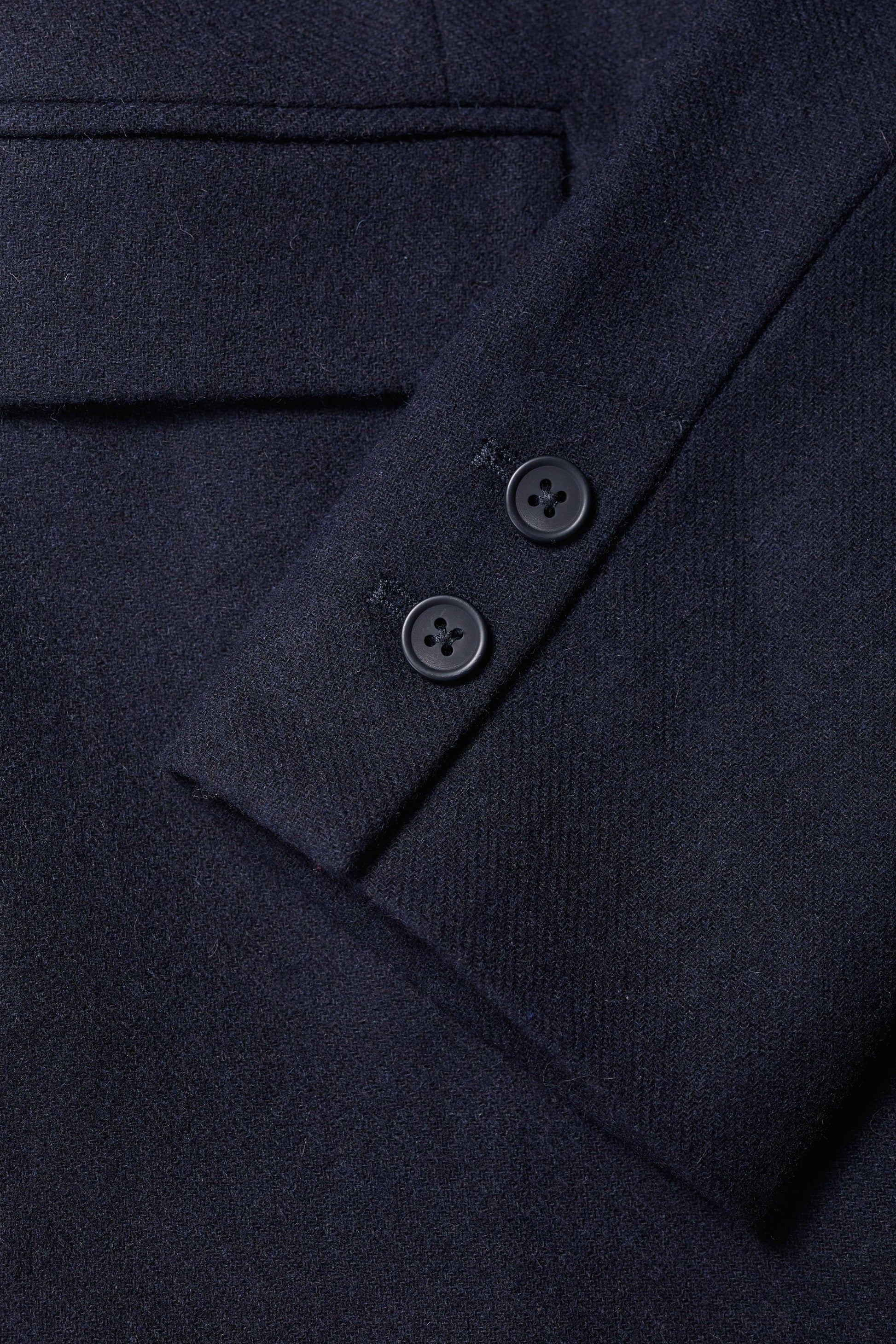 Close-up of a dark blue garment with buttons on a matching fabric background