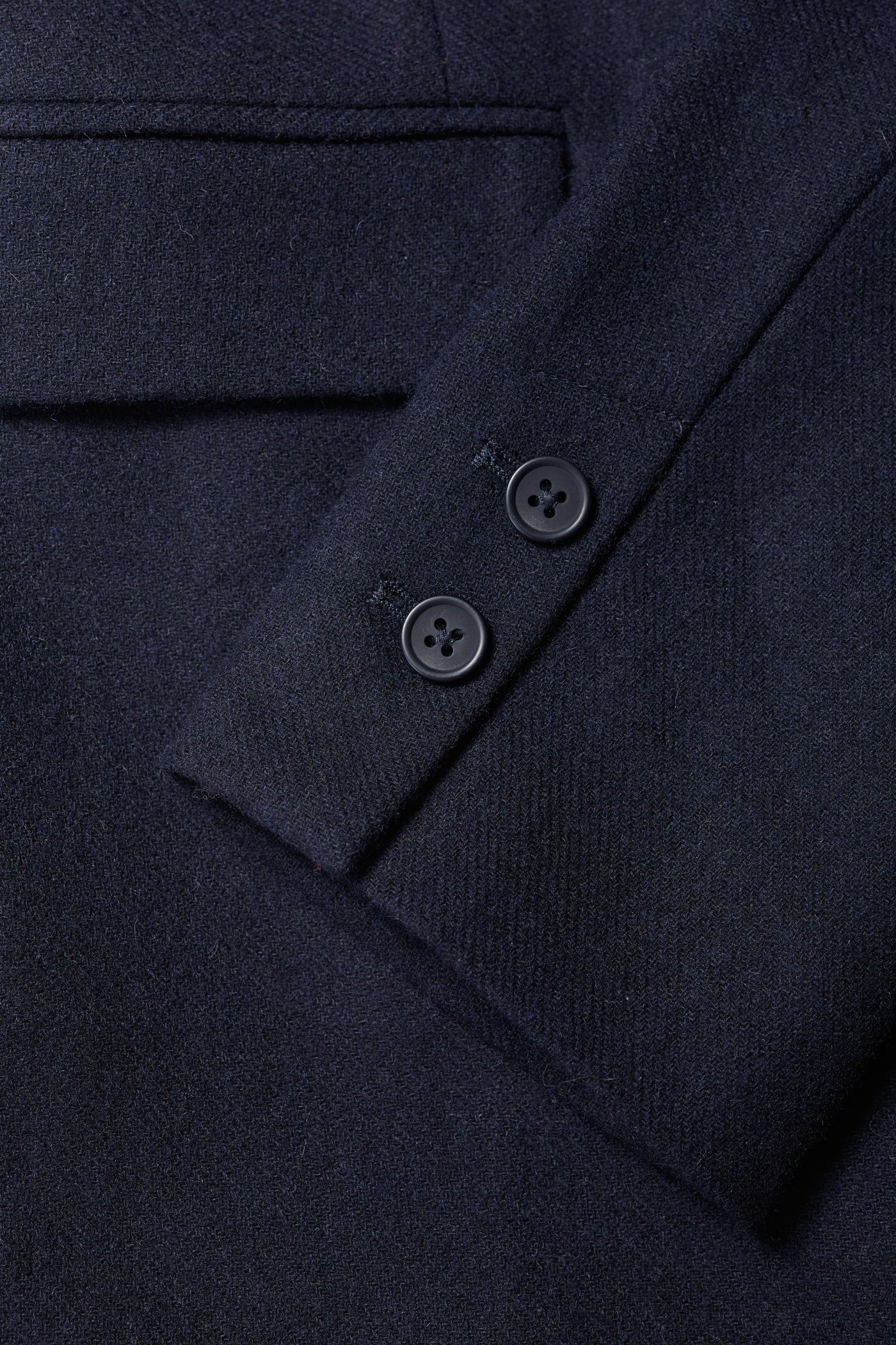 Close-up of a dark blue garment with buttons on a matching fabric background