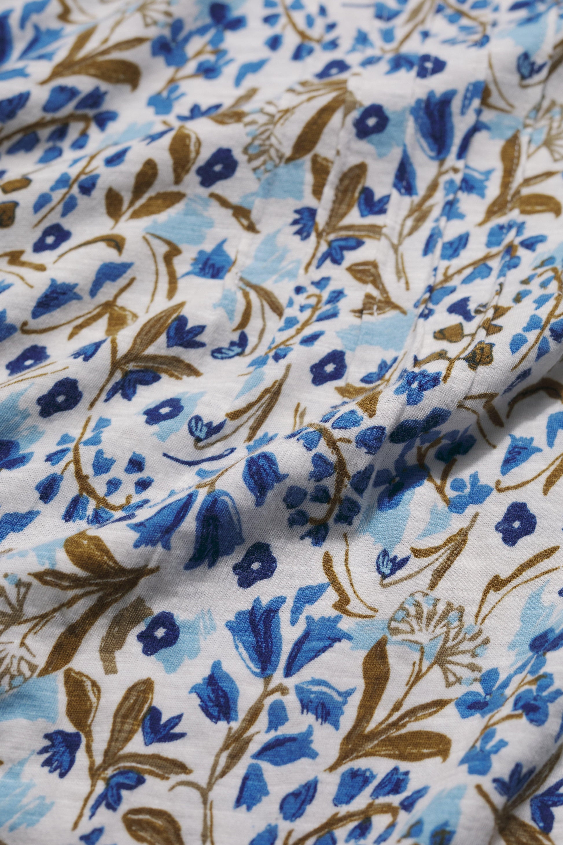 Close-up of floral organic cotton fabric with blue and brown patterns on a white background