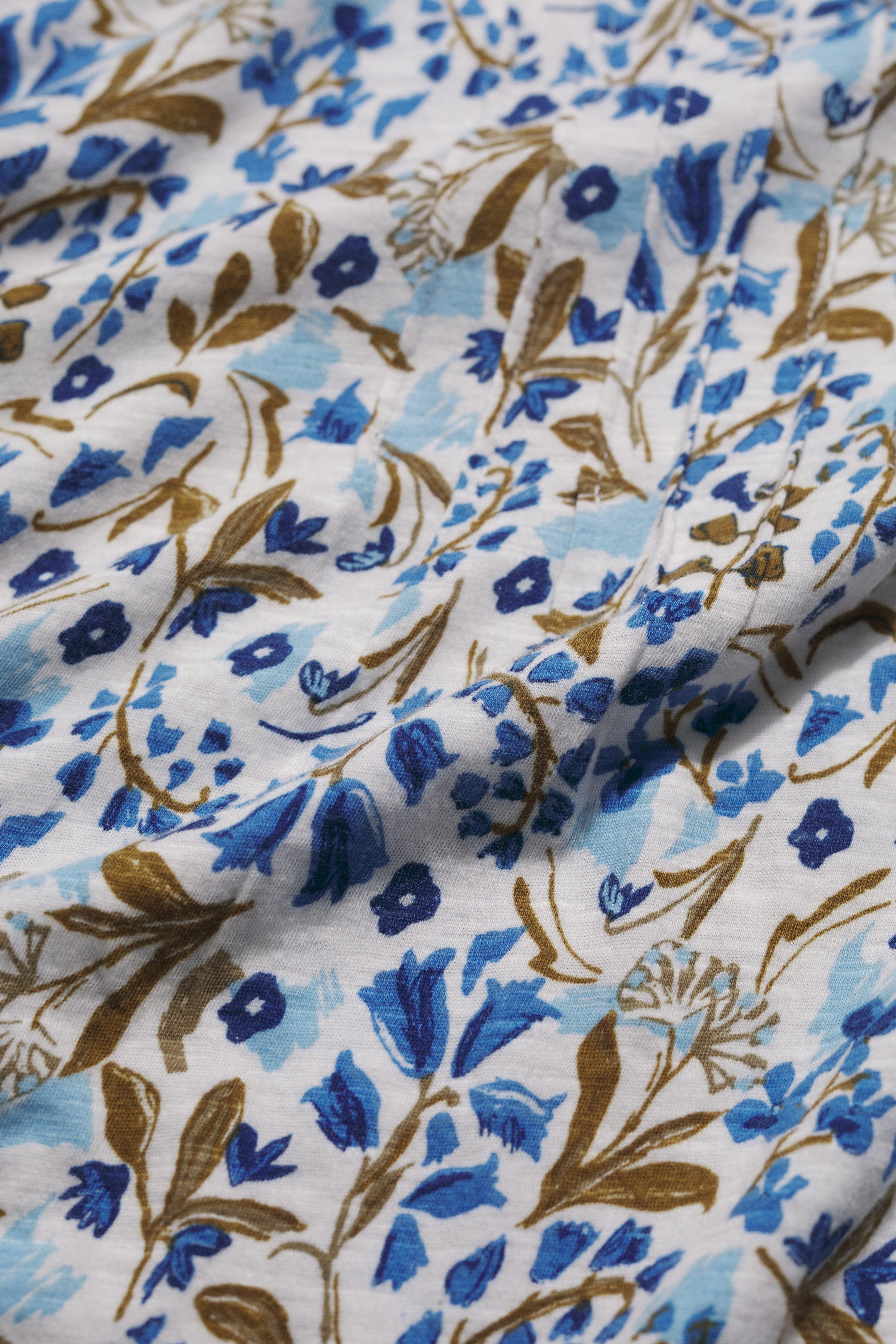 Close-up of floral organic cotton fabric with blue and brown patterns on a white background