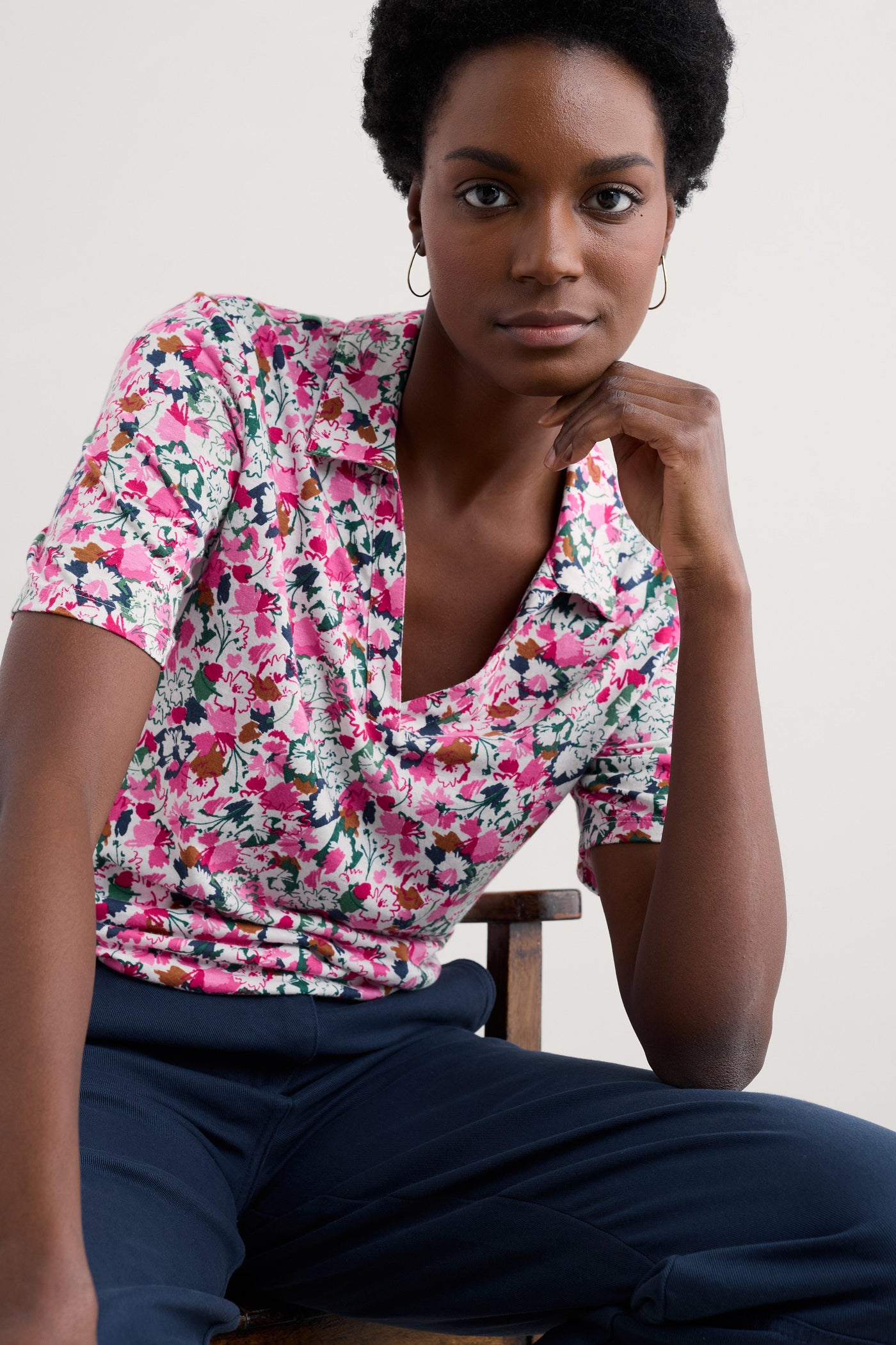 Model wearing the Seasalt Misty Sky Shirt in Blossom Sketch Chalk, featuring a collared V-neckline, short sleeves, and a relaxed fit, adorned with a vibrant floral print.
