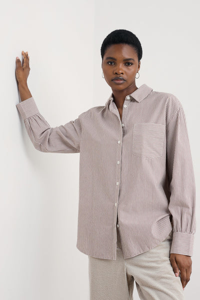 Woman wearing a striped organic cotton shirt and pants against a white background