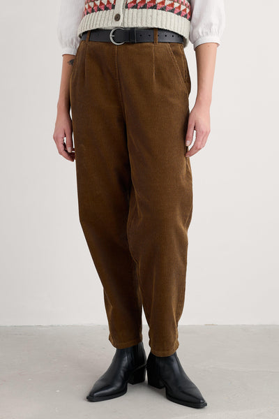 Person wearing brown organic cotton pants and black boots on a white background