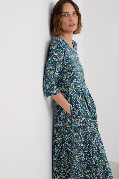 Woman wearing a long, patterned dress against a white background