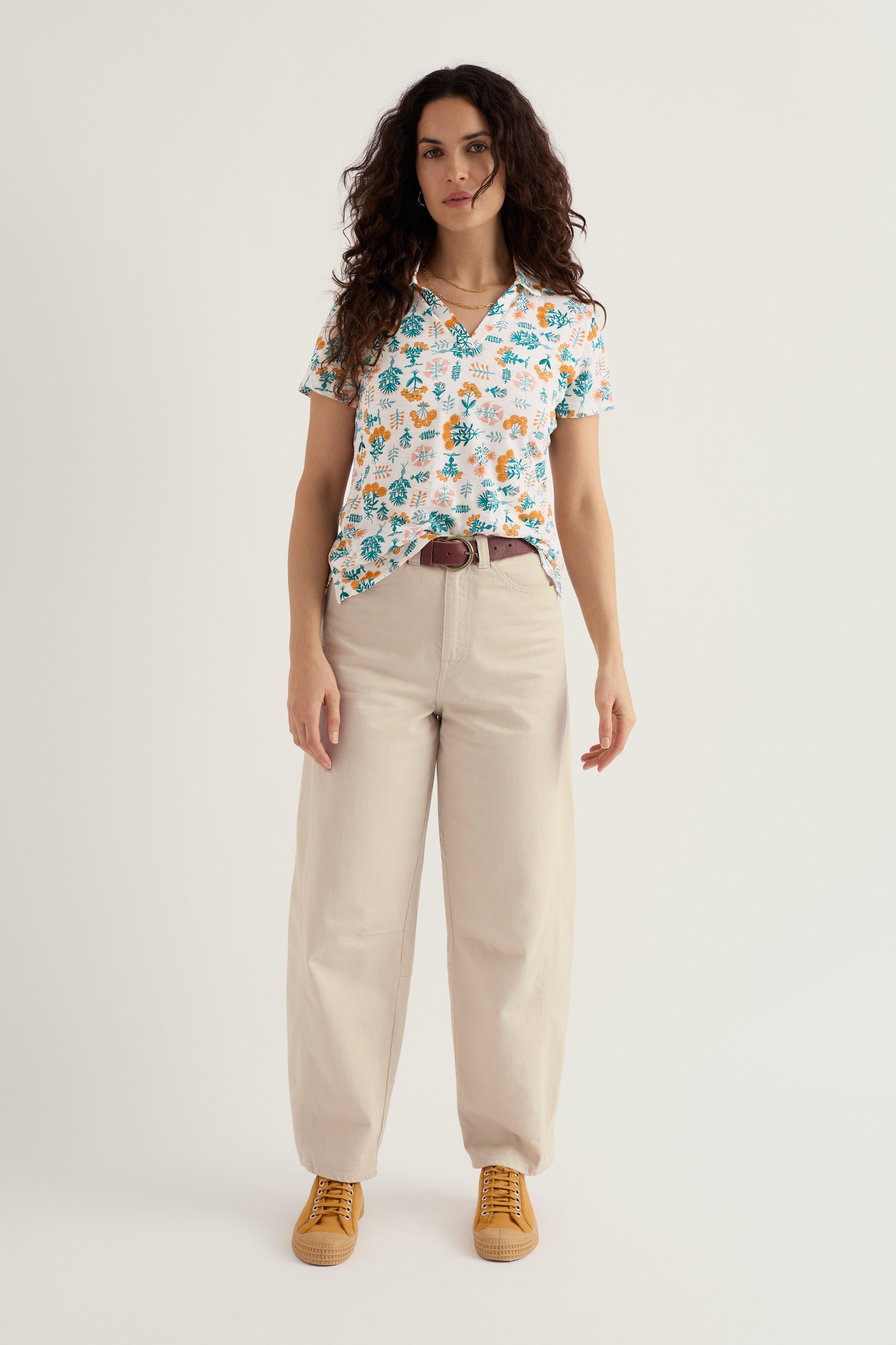 Woman wearing a patterned organic cotton shirt and beige pants on a white background