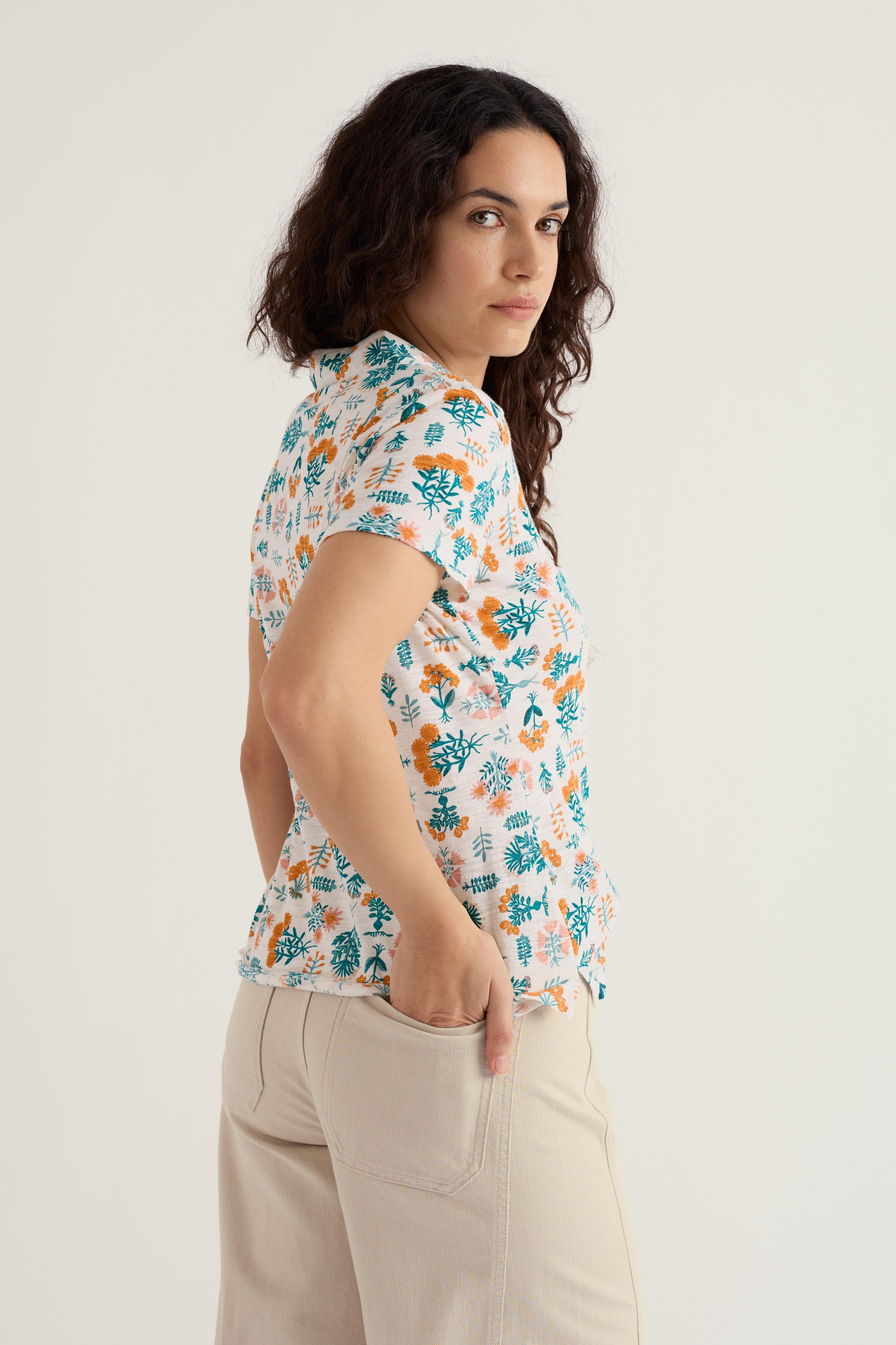 Woman wearing a floral short-sleeve shirt and beige barrel jeans on a light background
