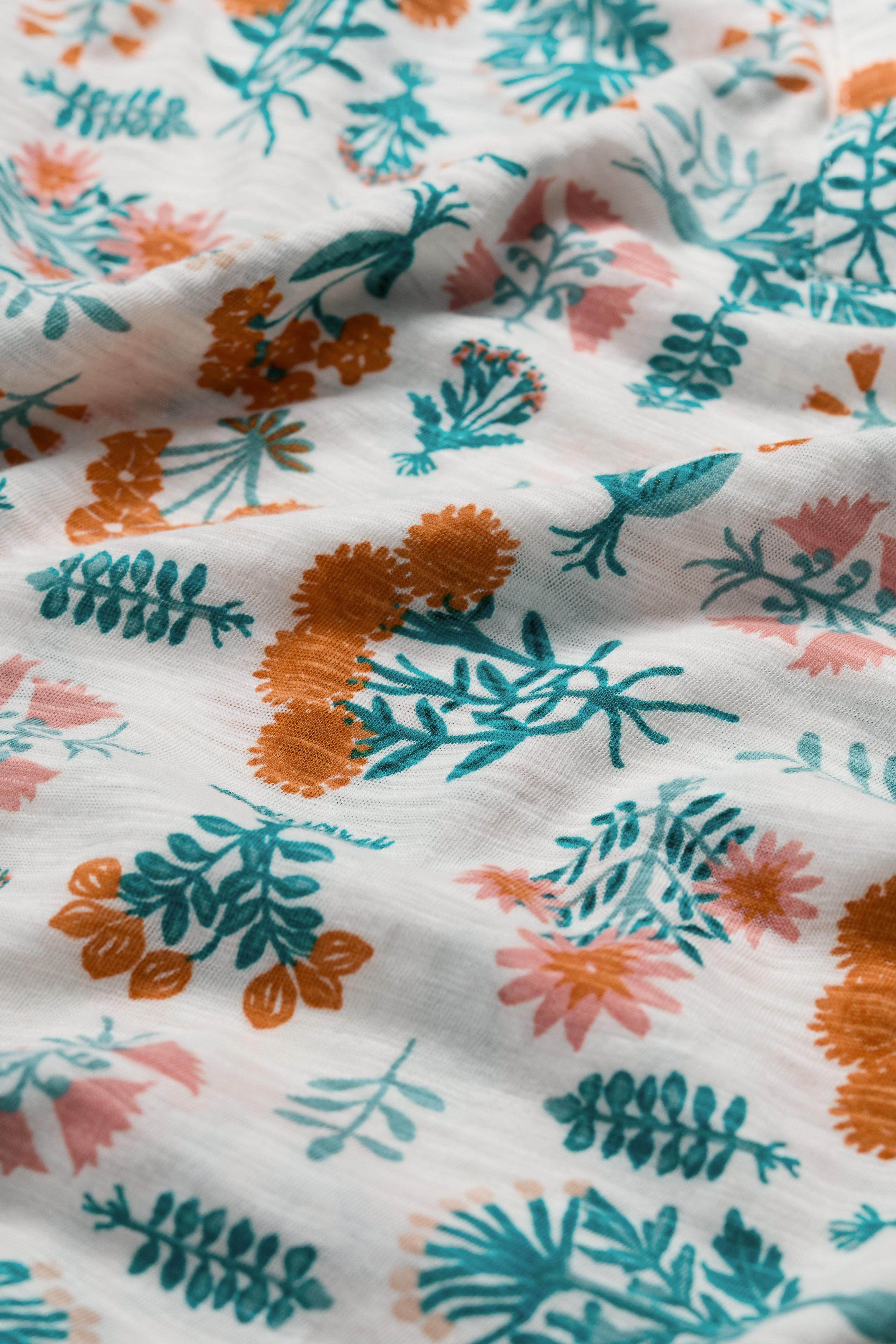 Floral patterned fabric with orange, green, and pink colors on a white background