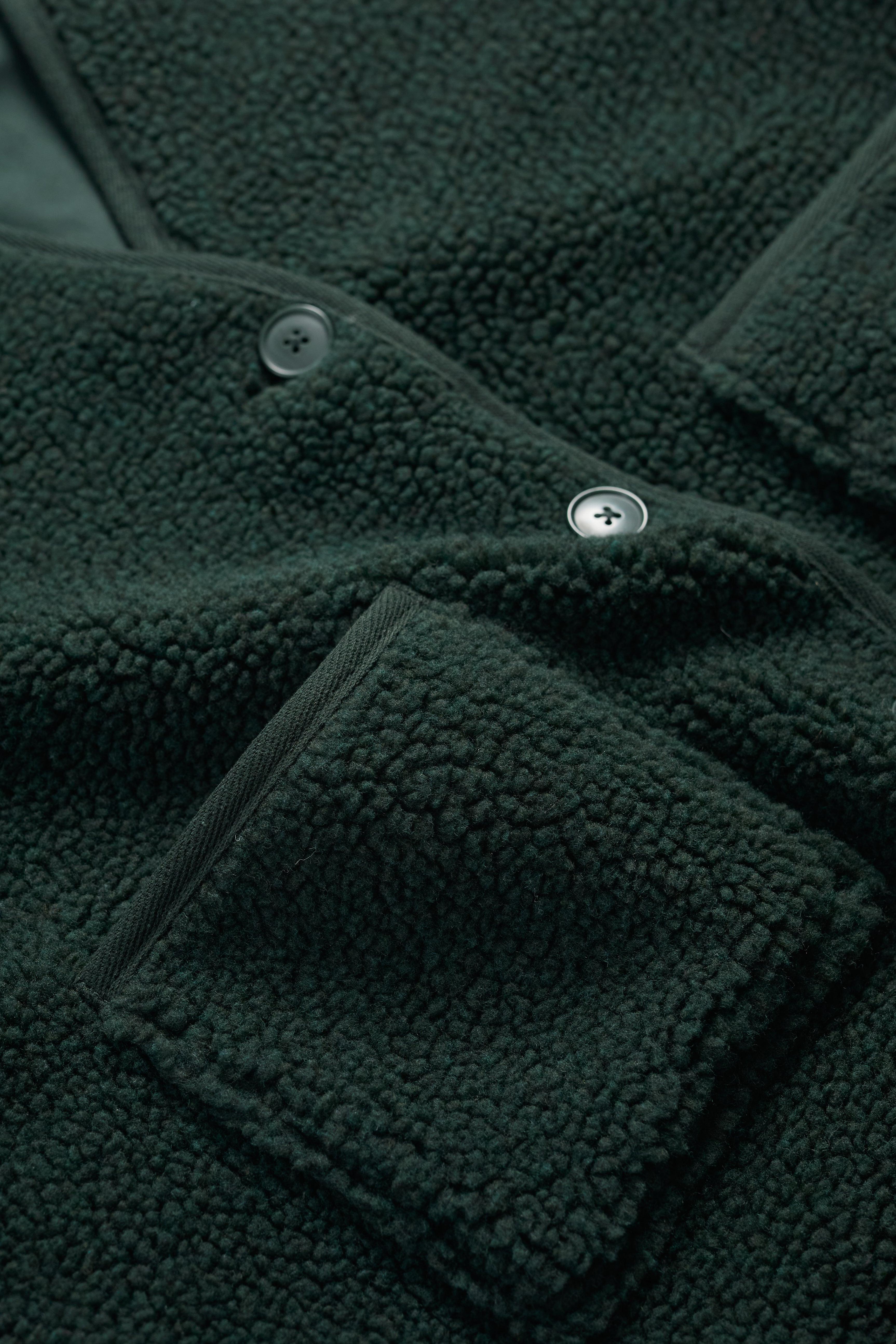 Close-up of a dark green fleece jacket with button details