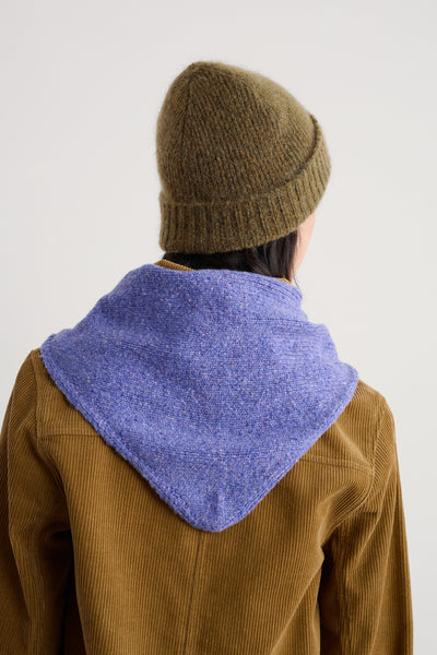 Person wearing a brown knitted hat and a brown jacket with a merino wool scarf against a white background