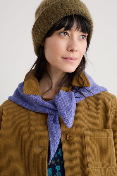 Person wearing a brown beanie and coat with a purple merino wool scarf on a white background