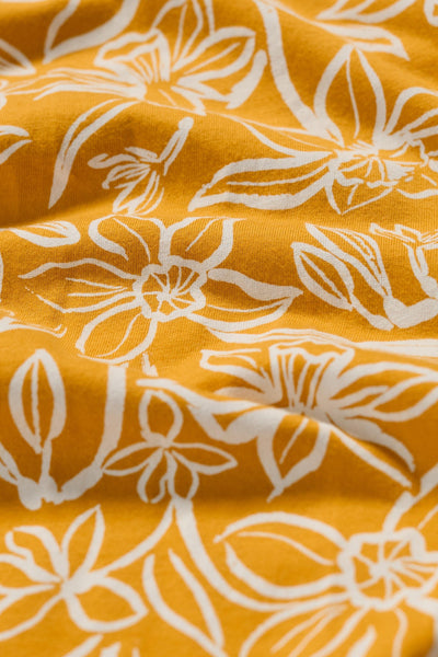  Close-up of the yellow organic cotton fabric showing detailed white floral pattern.