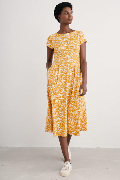 Full-length front view of model in yellow organic cotton Seasalt dress, with hands at sides.