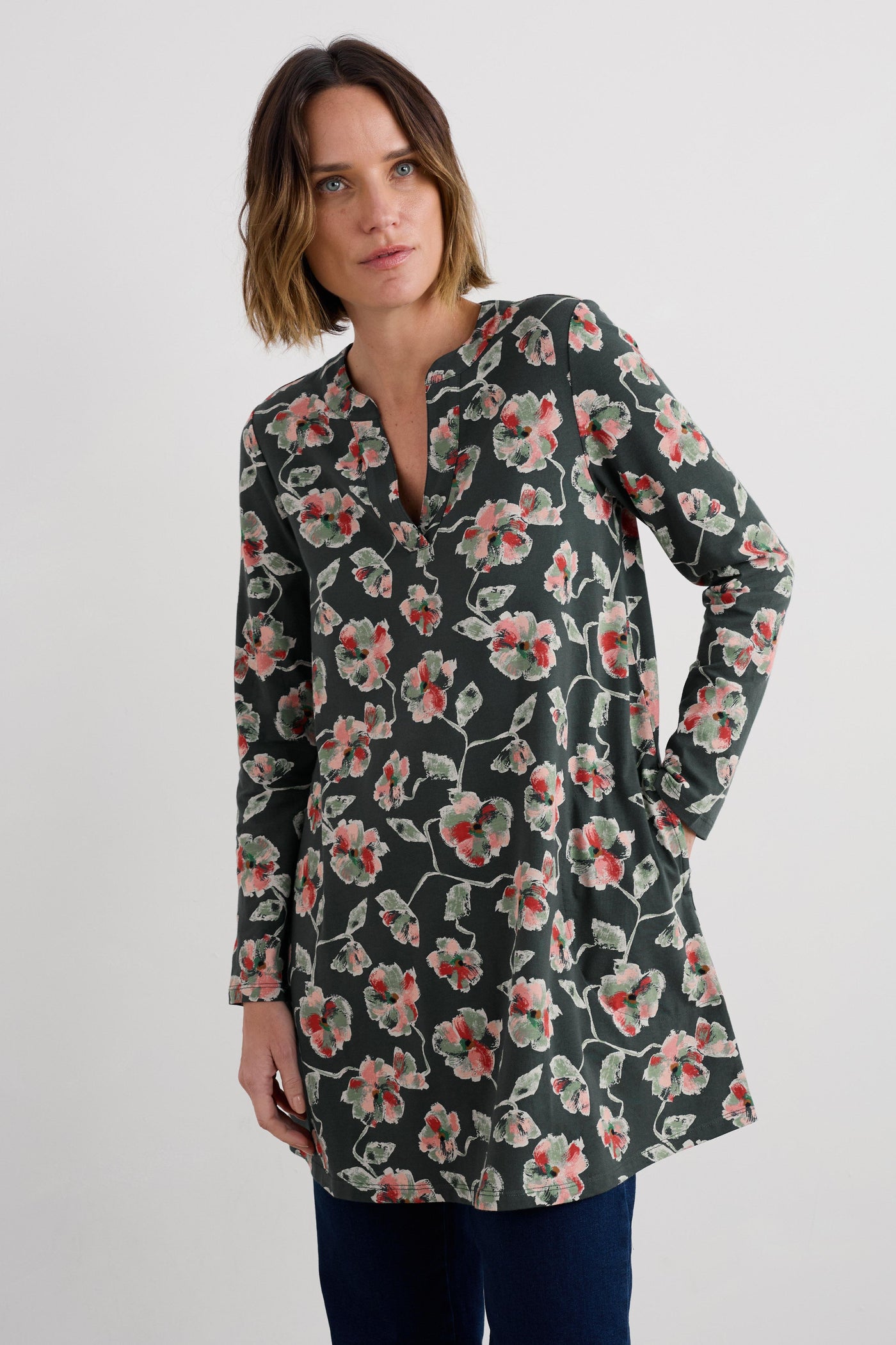 Woman wearing a floral long-sleeve tunic against a white background