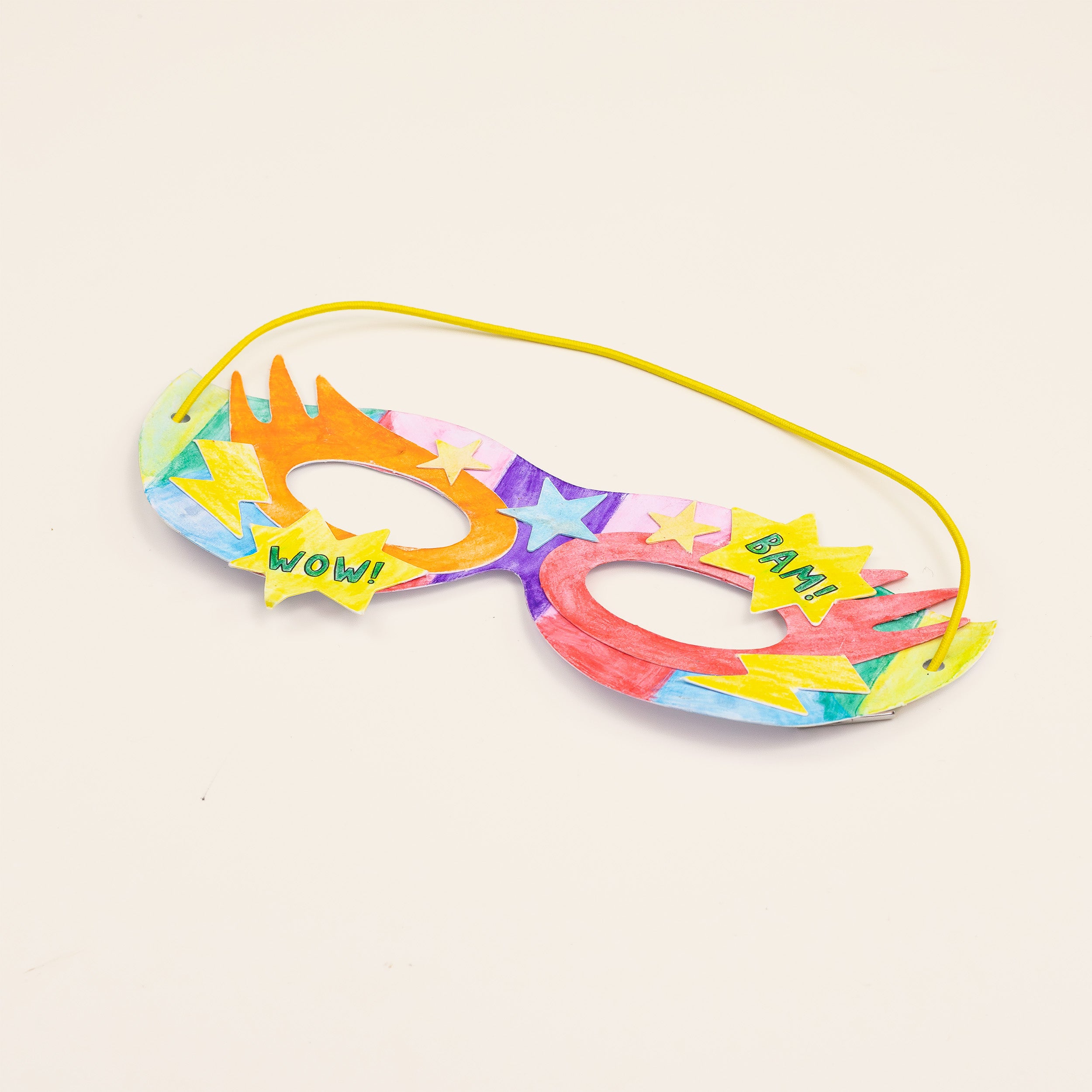 Handmade colorful paper superhero mask with comic book style text.