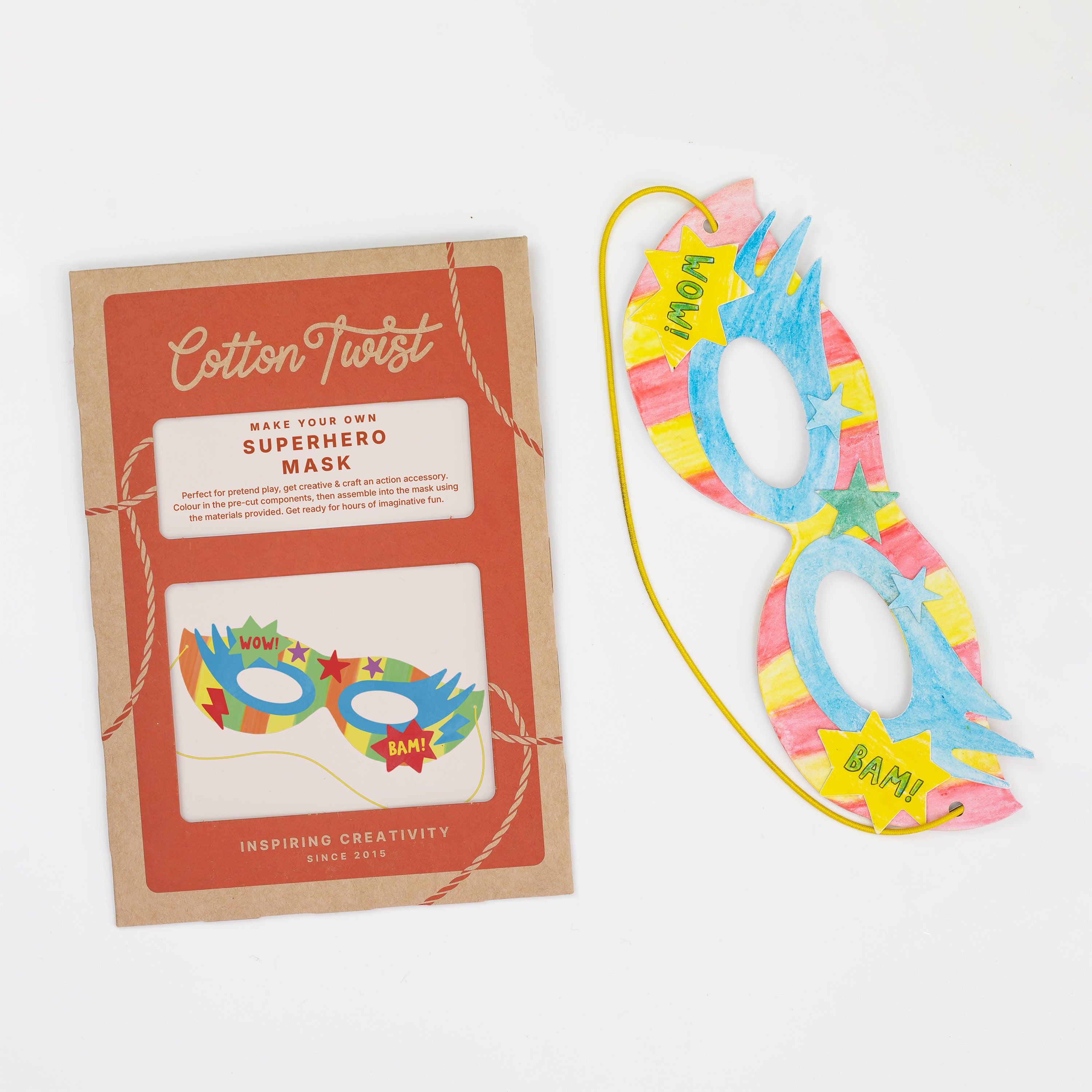 A DIY superhero mask craft kit with a colorful hand-decorated cardboard mask and product packaging.