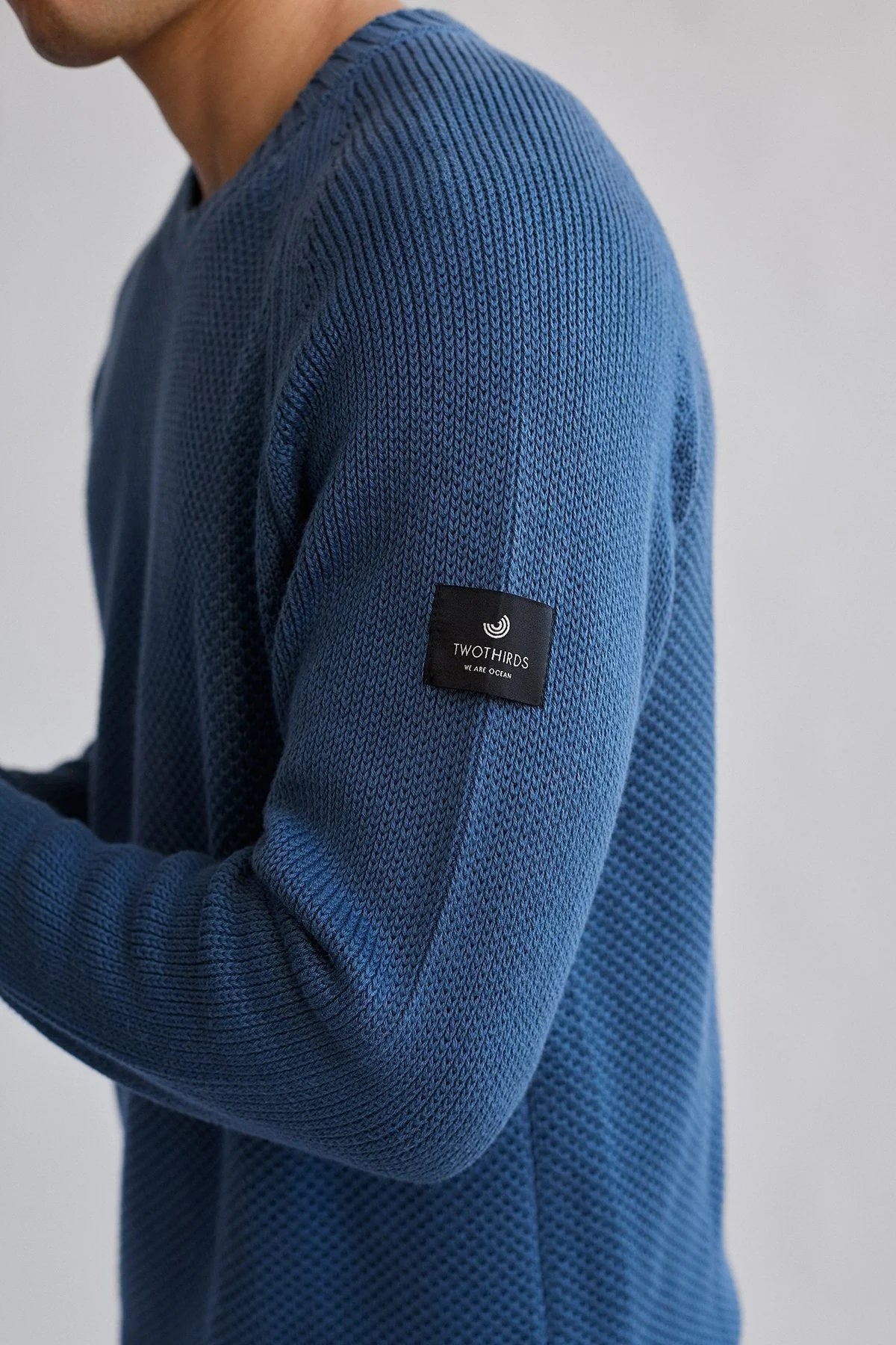 Close up of organic cotton fabric and TWOTHIRDS logo on a black square tag.