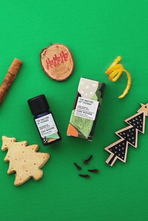 Christmas-themed items including a bottle, packaging, cookies, and wooden ornaments on a green background
